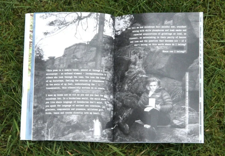 Open book on grass showing a black and white photograph of a woman sitting outdoors holding a notebook, with text overlay. The background includes rocky terrain and trees.