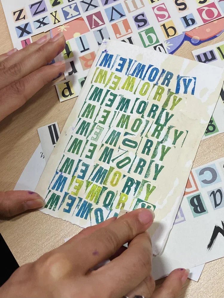 Sheet of colorful alphabet and memory game stickers about the word 'memory' in various colors and fonts, with some hands peeling off a sticker.