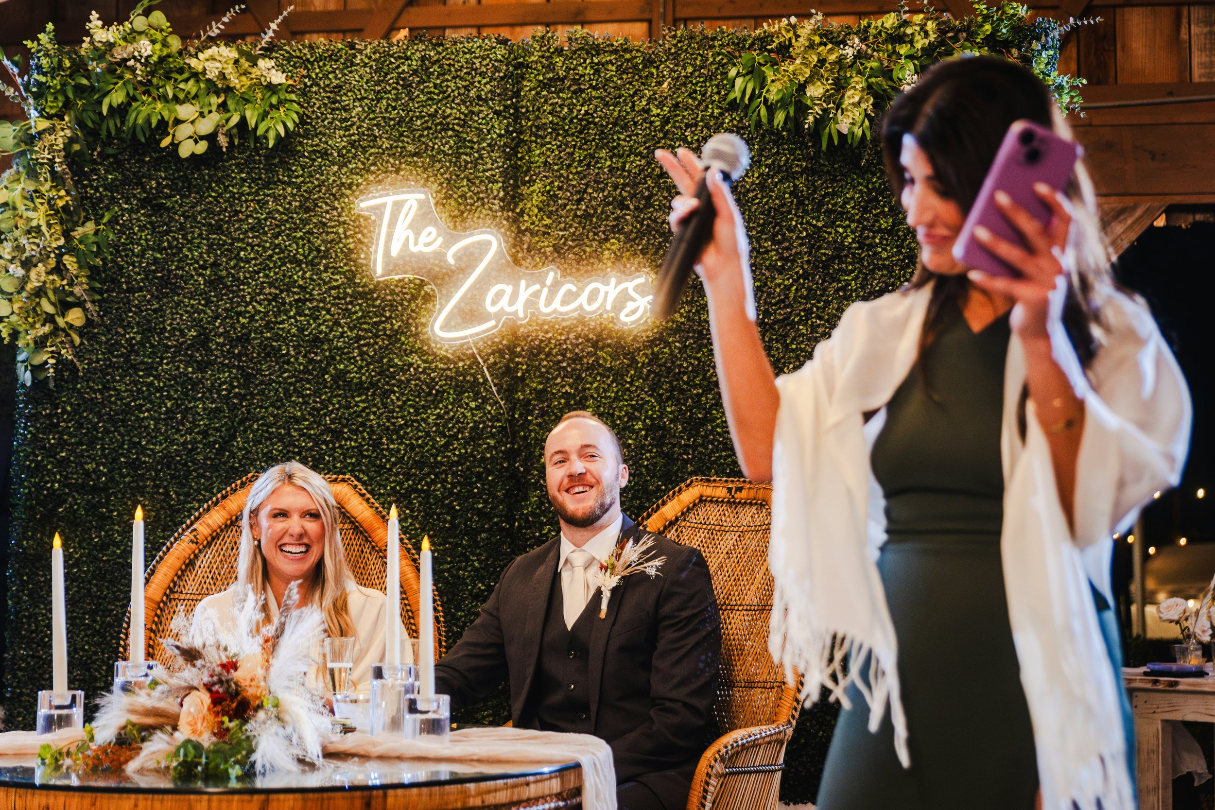 A wedding guest giving a heartfelt speech during the reception as the bride and groom smile from the top table.