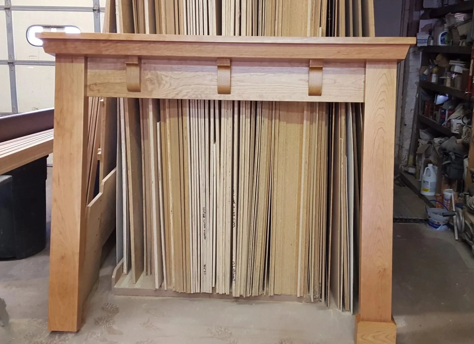 Wooden furniture piece holding multiple wooden slats or moldings in a woodworking shop.