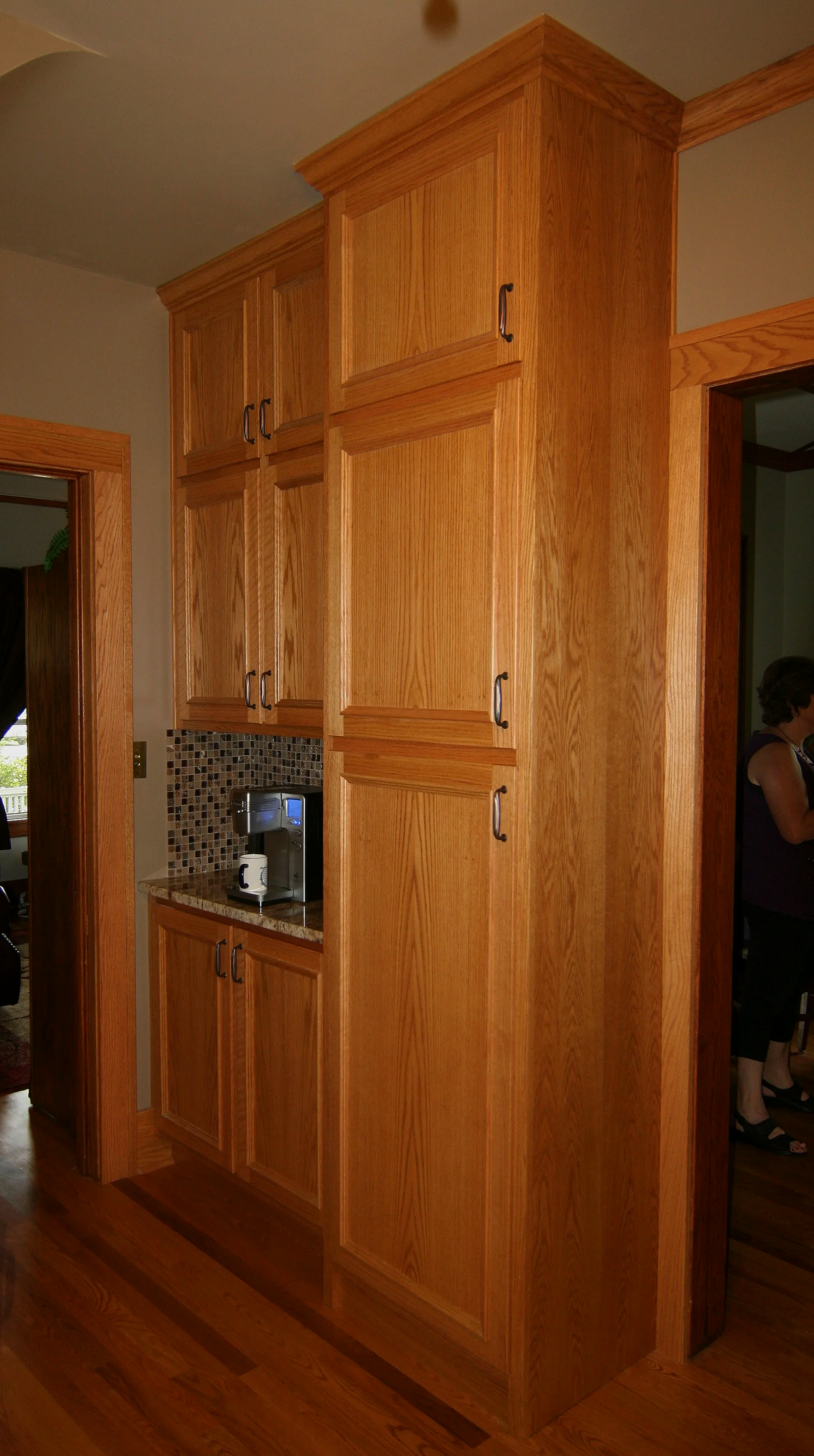 Wooden kitchen cabinets with a coffee maker on the countertop and a mosaic tile backsplash.