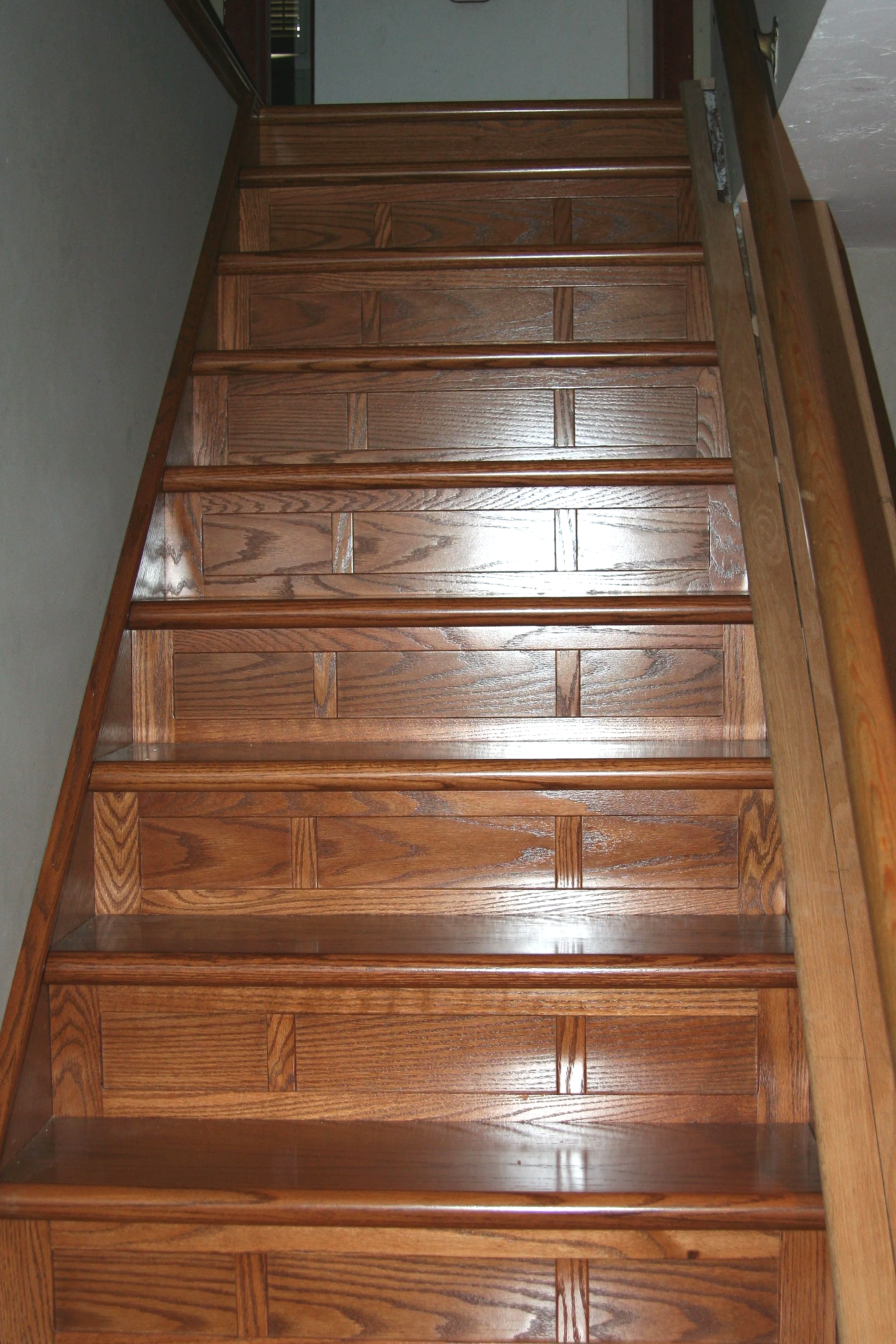 Wooden staircase with polished steps viewed from below.
