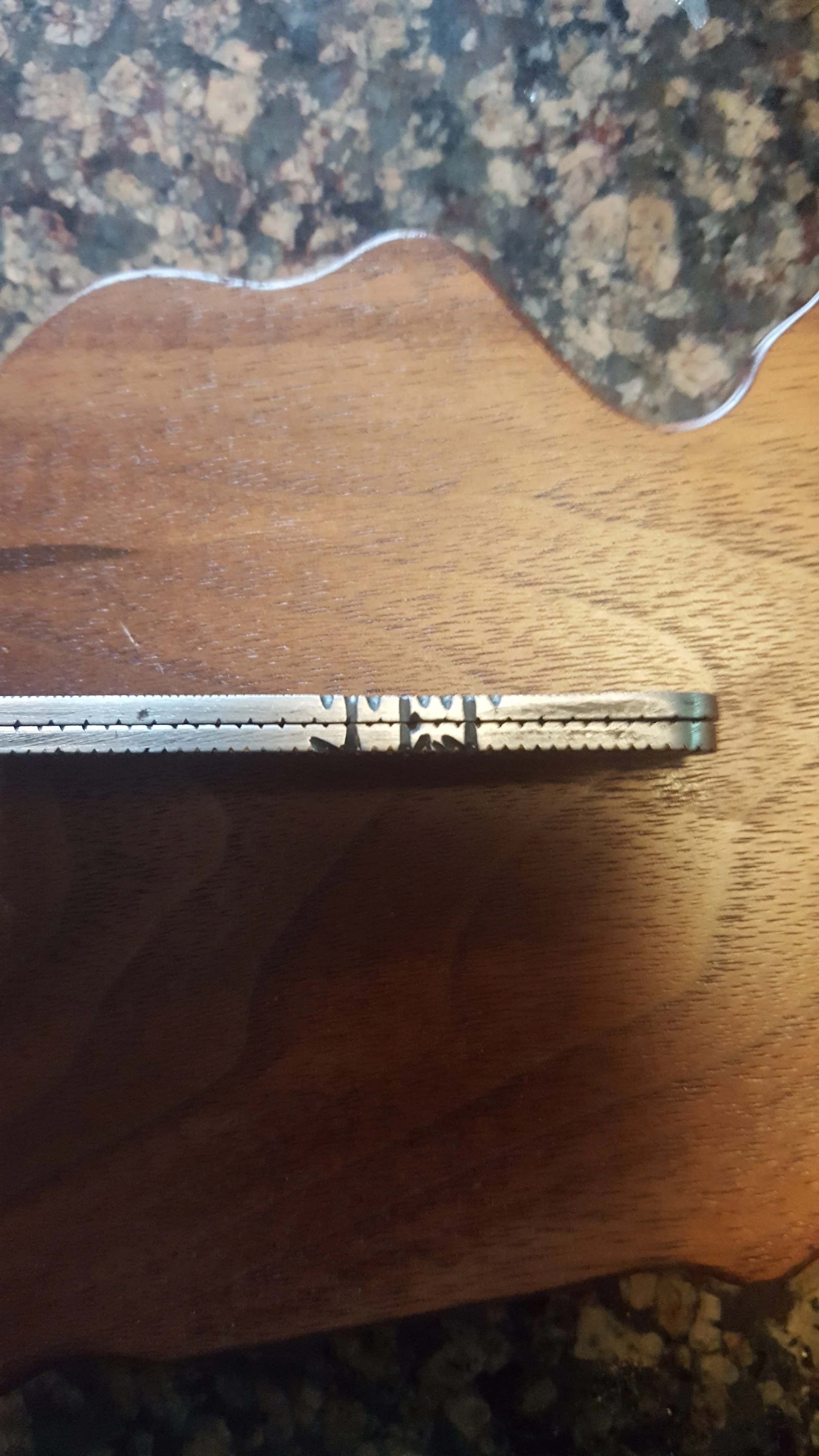 Close-up of a hockey puck resting on a wooden surface, with part of a granite countertop visible at the top.