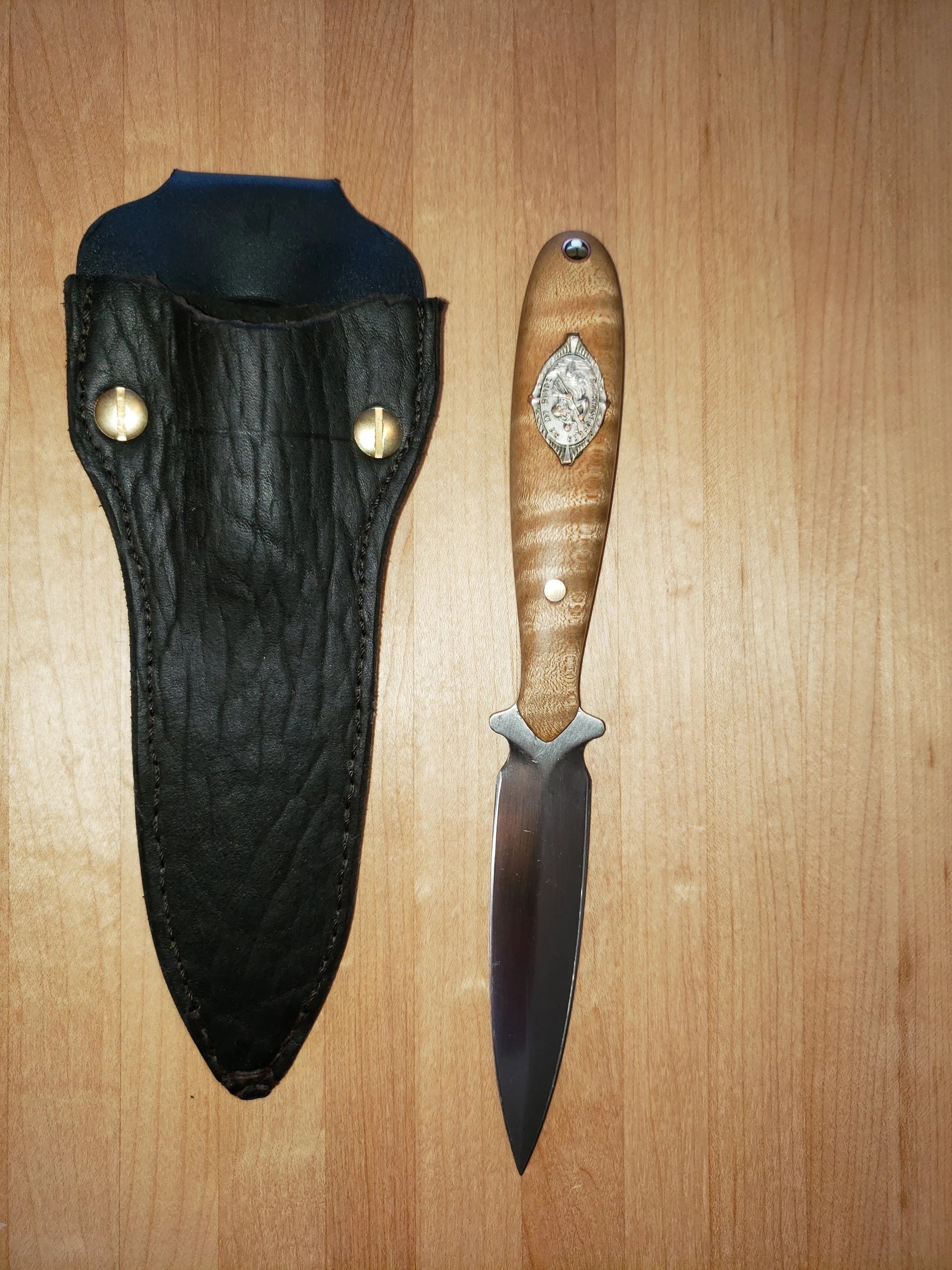 A folding pocket knife with a decorative handle and a leather sheath.