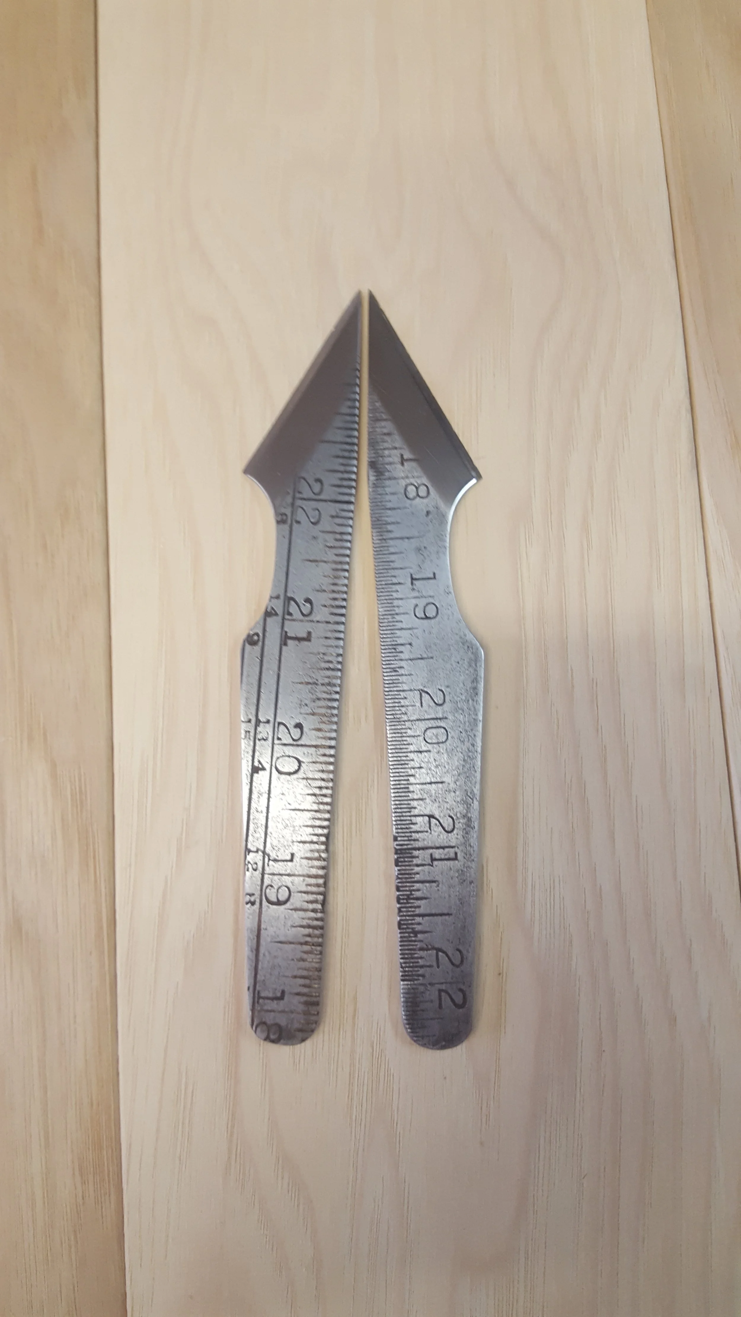 A metal folding ruler with the two segments extended and aligned to form an L-shape, resting on a wooden surface.