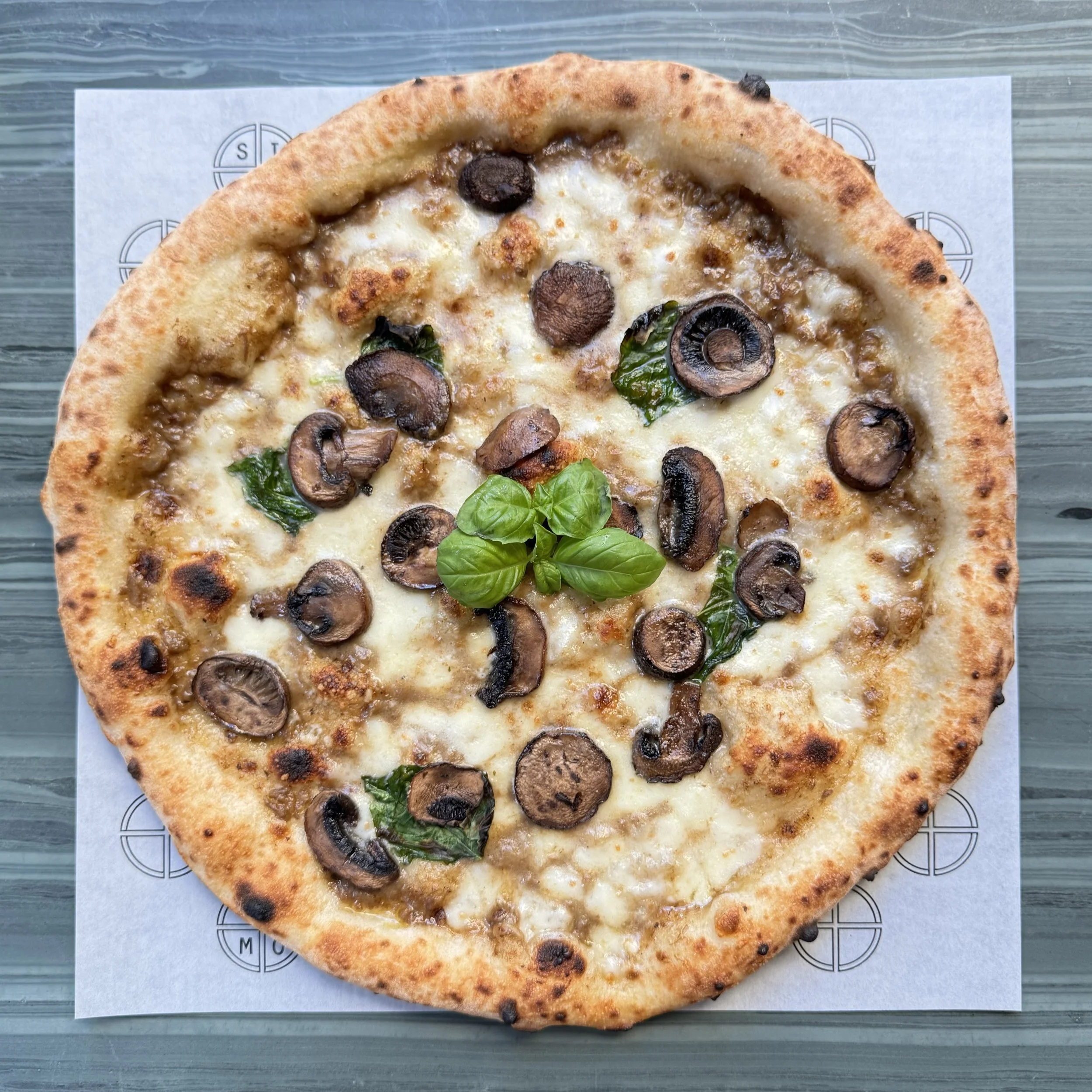 Pizza with mushrooms, spinach, and basil on top
