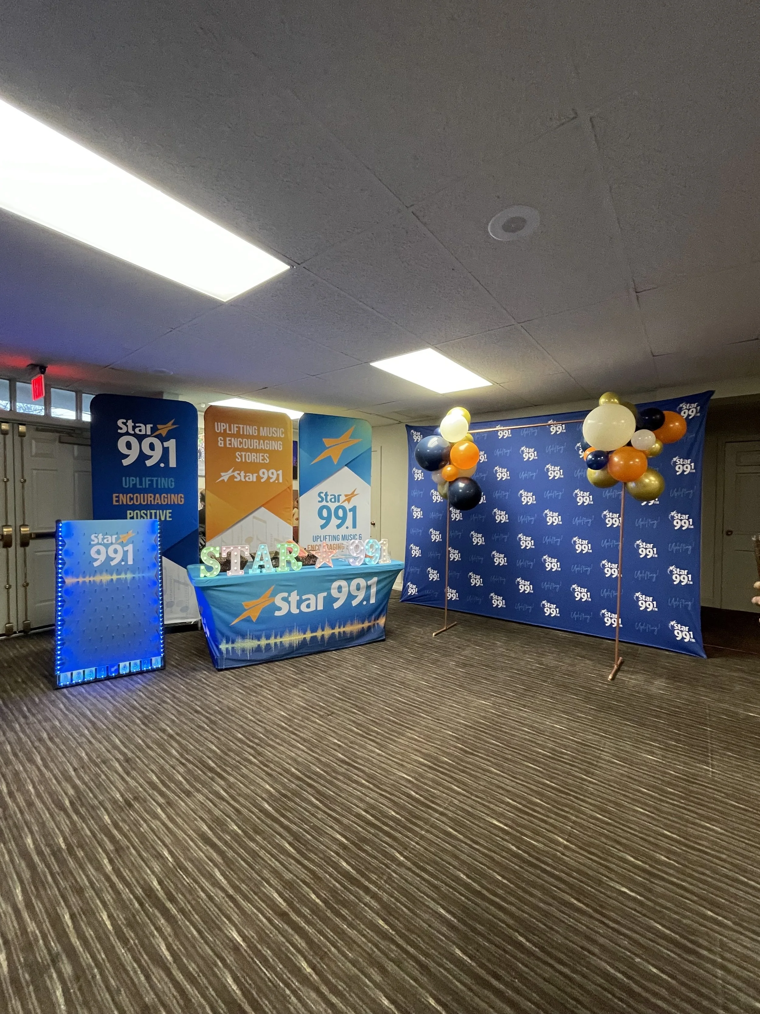 Event setup with a Star 99.1 banner, balloons, and decorative props for a promotional or celebratory event.