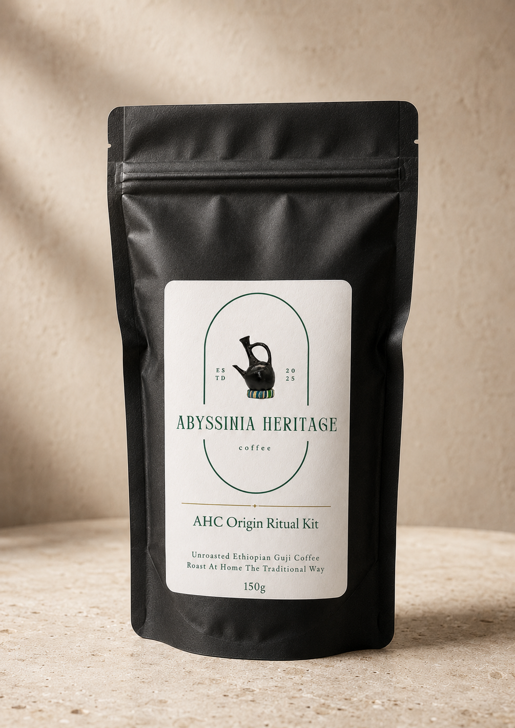 Black package of Abyssinia Heritage coffee with a white label featuring a black kettlebell and colorful bracelet, sitting on a beige surface against a beige background.