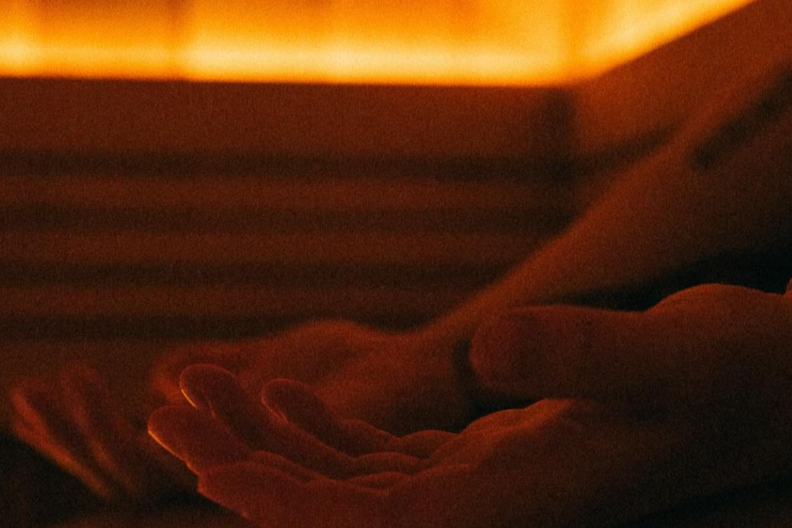 Close-up of a person's hand flipping through pages of a book at sunset or in warm lighting.