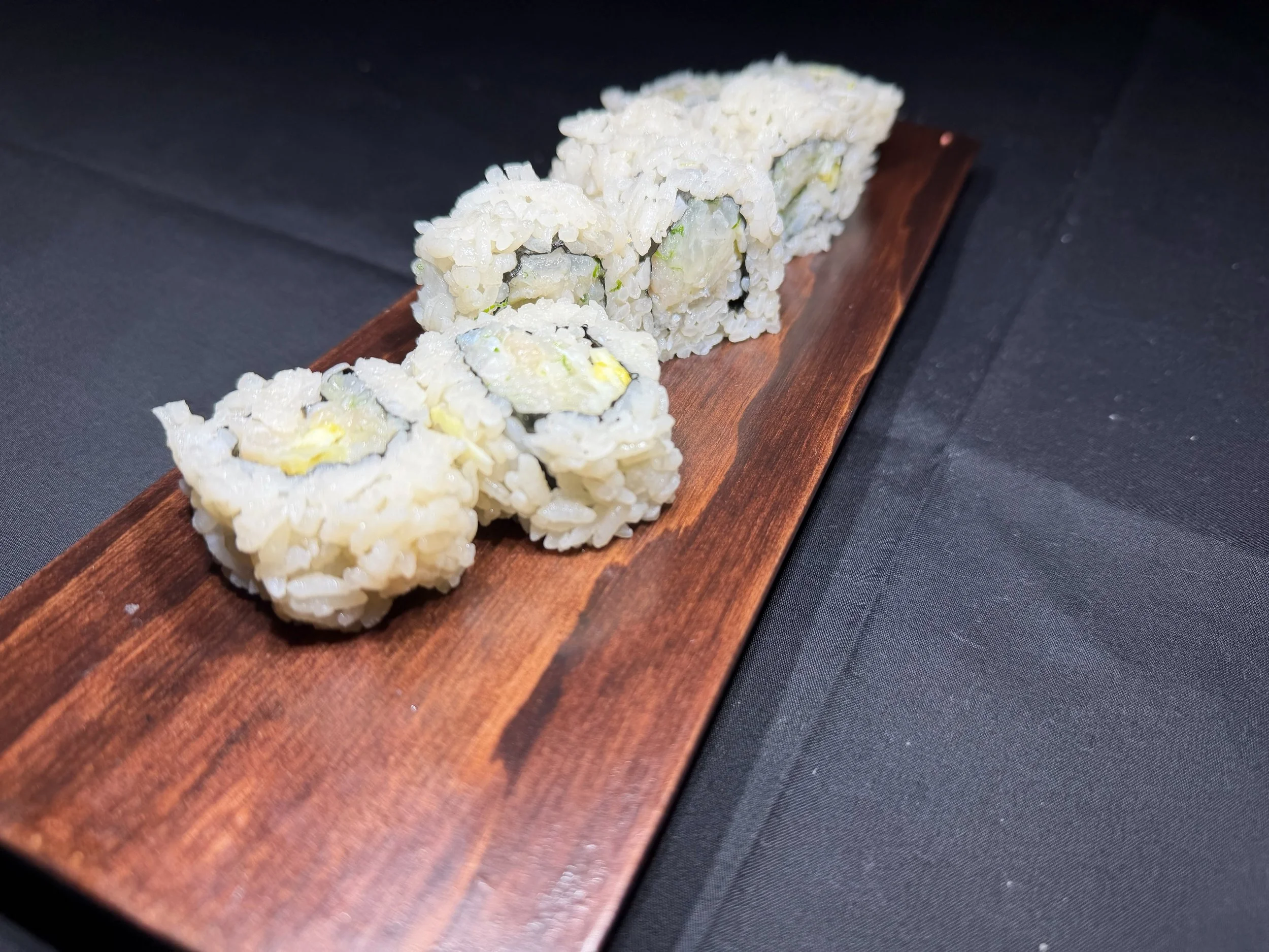 Sushi rolls on a wooden serving board.