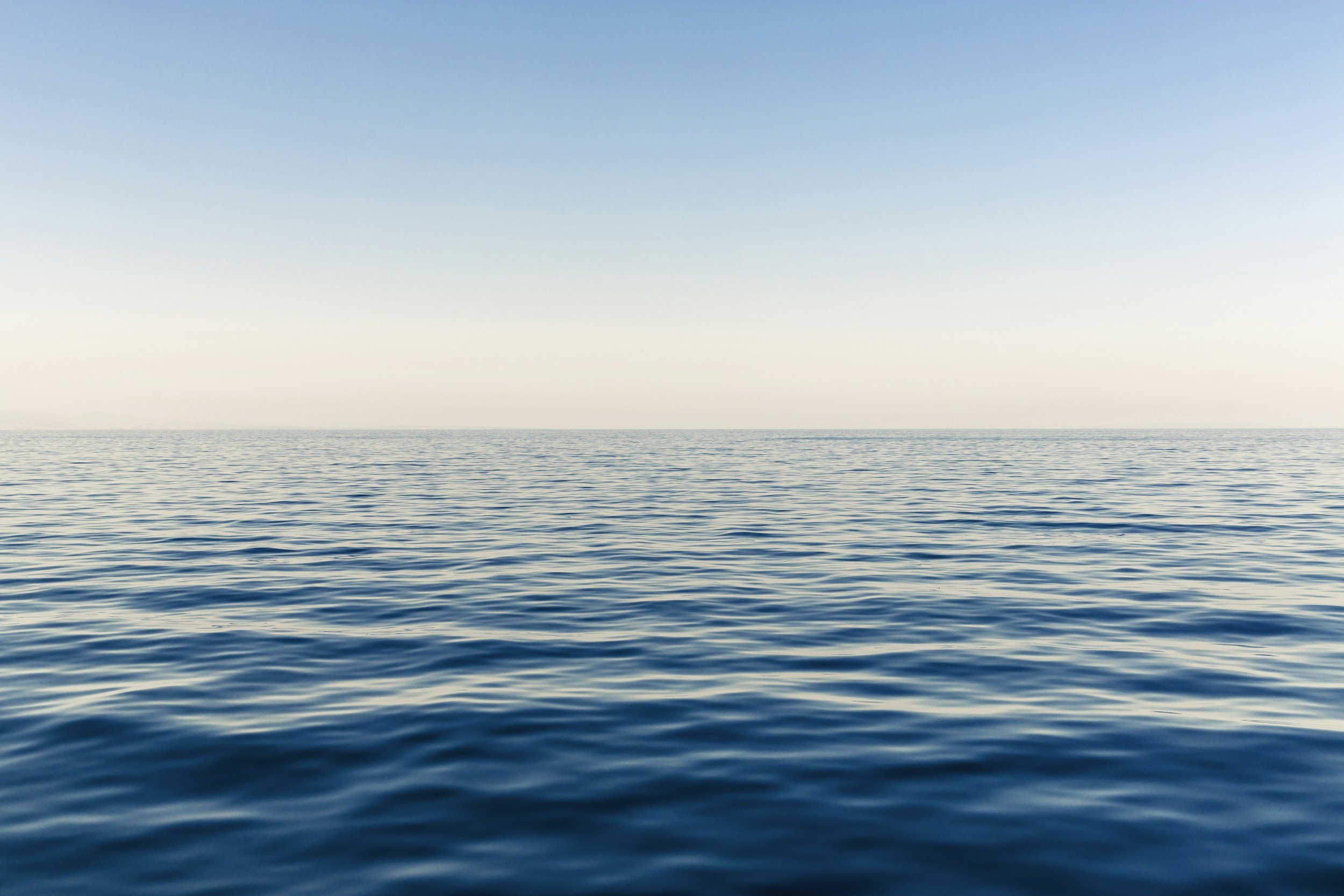 Calm ocean water with gentle ripples under a clear, blue sky.
