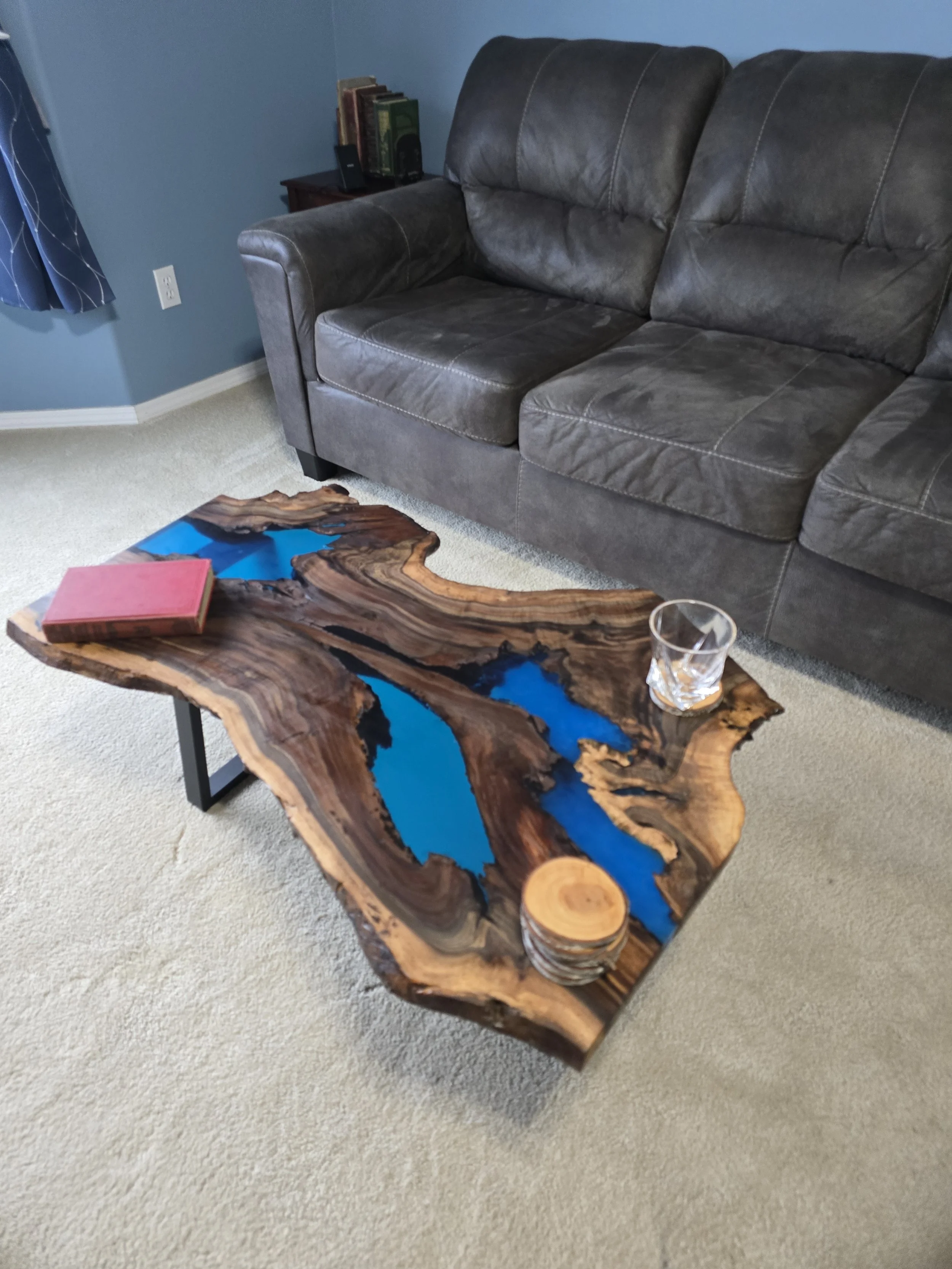 Black walnut coffee table with metal table legs and adjustable feet. Semitransparent blue epoxy fills voids. Measures 18 inches tall, 36 inches long, and 24 inches wide.