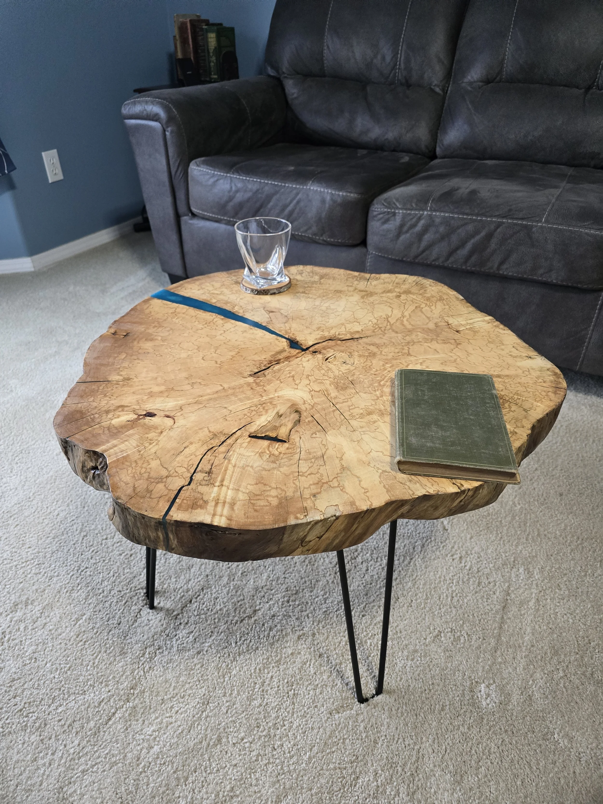live edge table made from a maple round with blue epoxy and hair pin legs.