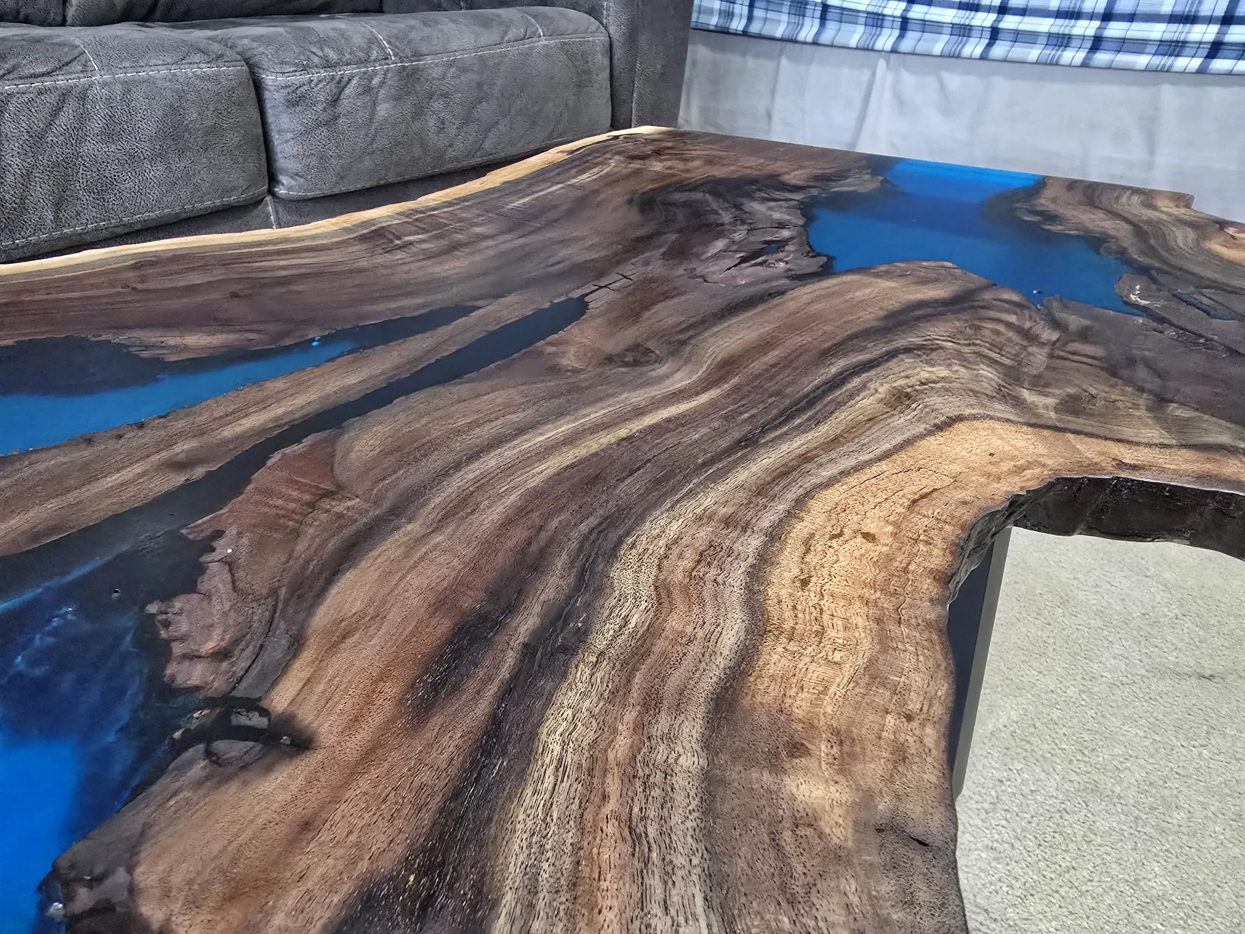 Black walnut coffee table with metal table legs and adjustable feet. Semitransparent blue epoxy fills voids. Measures 18 inches tall, 36 inches long, and 24 inches wide.