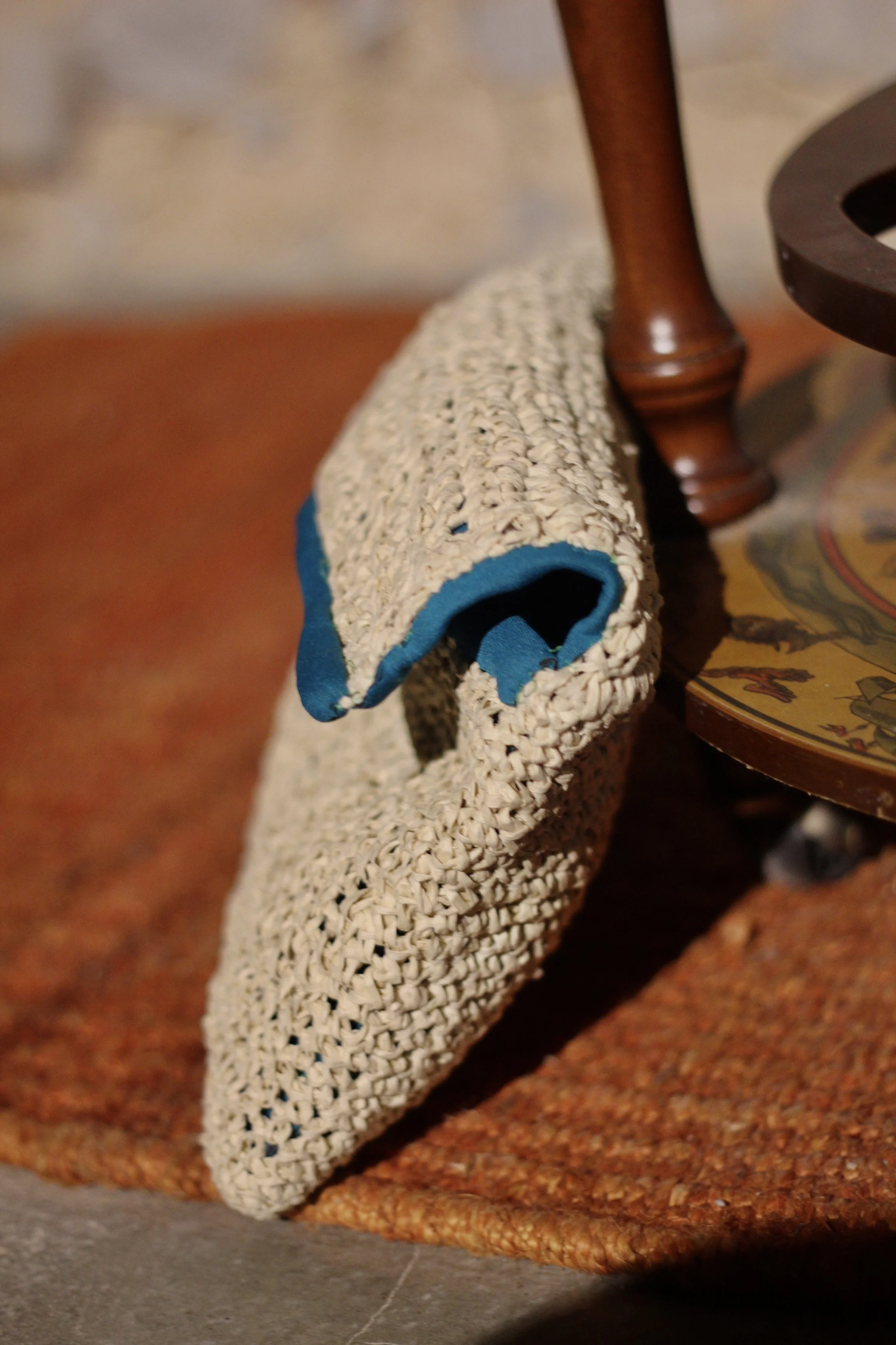 Una cartera de mano en rafia y forro de neopreno verde sobre una mesa de madera.