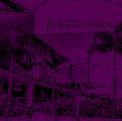 Sign that reads "Welcome to the boulevard" with icons of a fork, knife, and spoon, surrounded by palm trees and a shopping mall mall interior.