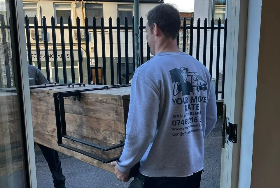 The guys from your move mate man a van removals service carry a large desk in an office move