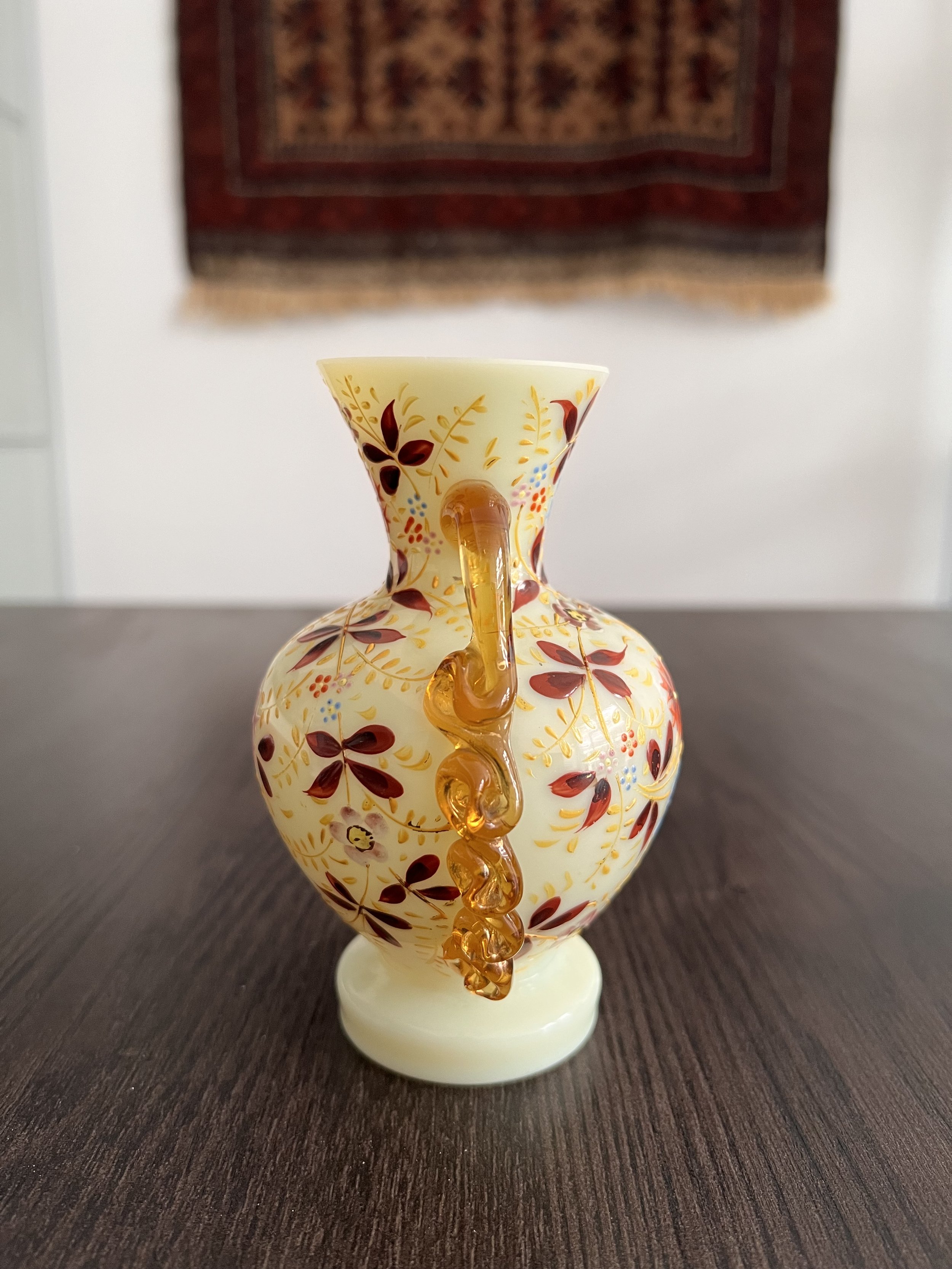 Antique ivory opaline glass vase with hand-painted enamel floral decoration, gilt accents, and applied amber glass handles, circa 1900.