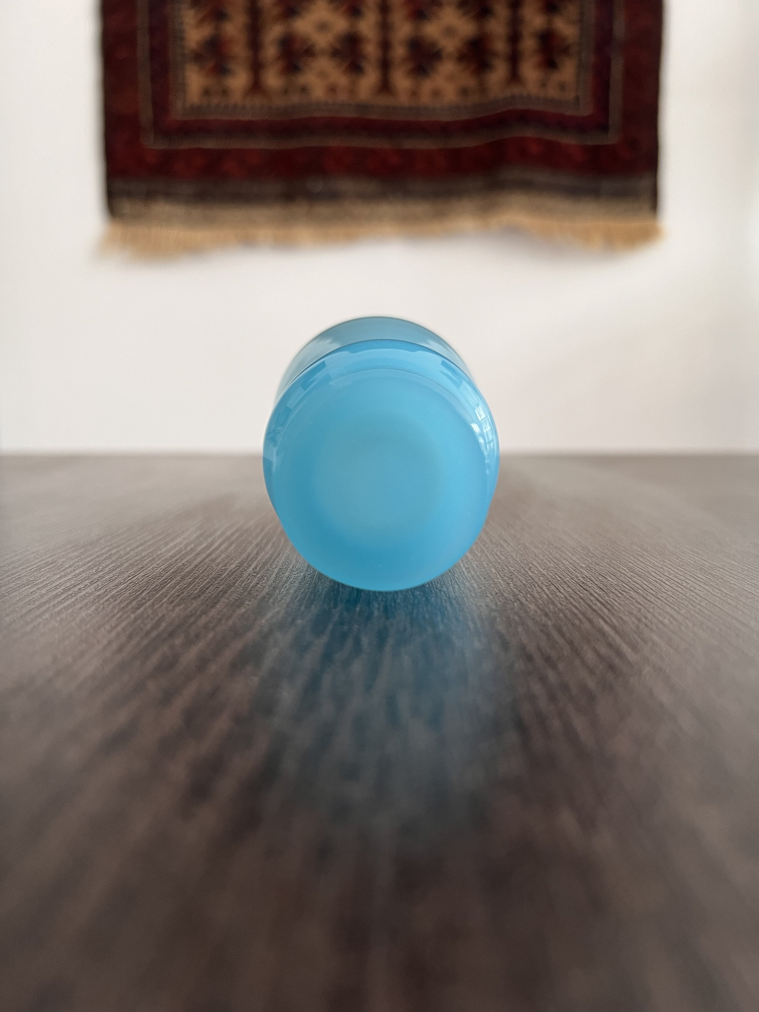 Small mid-century vintage baby blue opaline glass vase with a flared trumpet neck, bulbous spherical base, and short pedestal foot, displayed on a dark wooden table background.