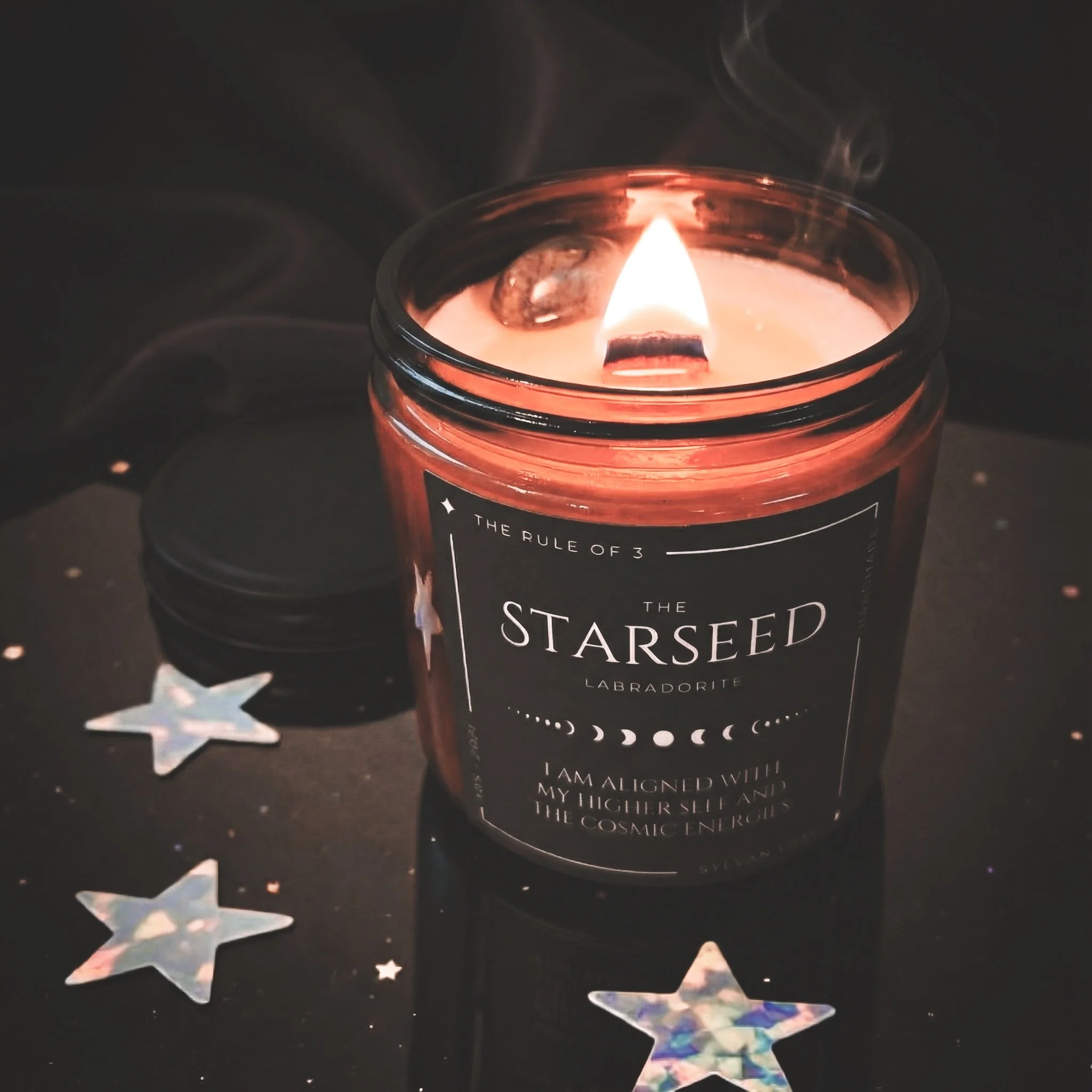 “Lit Starseed ritual candle with a crackling wood wick, styled against a starry cosmic background.”