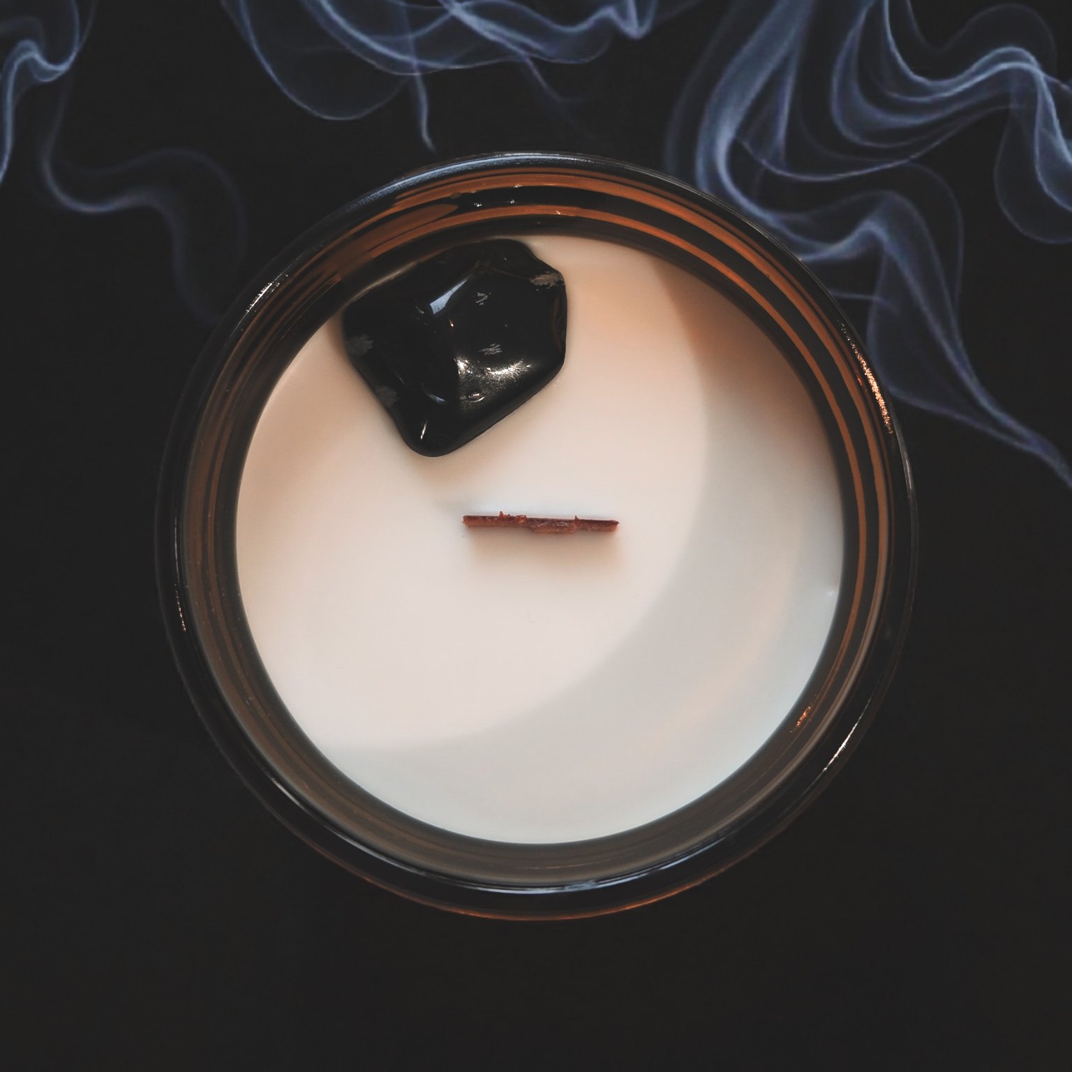 “Top view of the Nag Champa candle featuring snowflake obsidian crystals embedded in soy wax with a wood wick.”