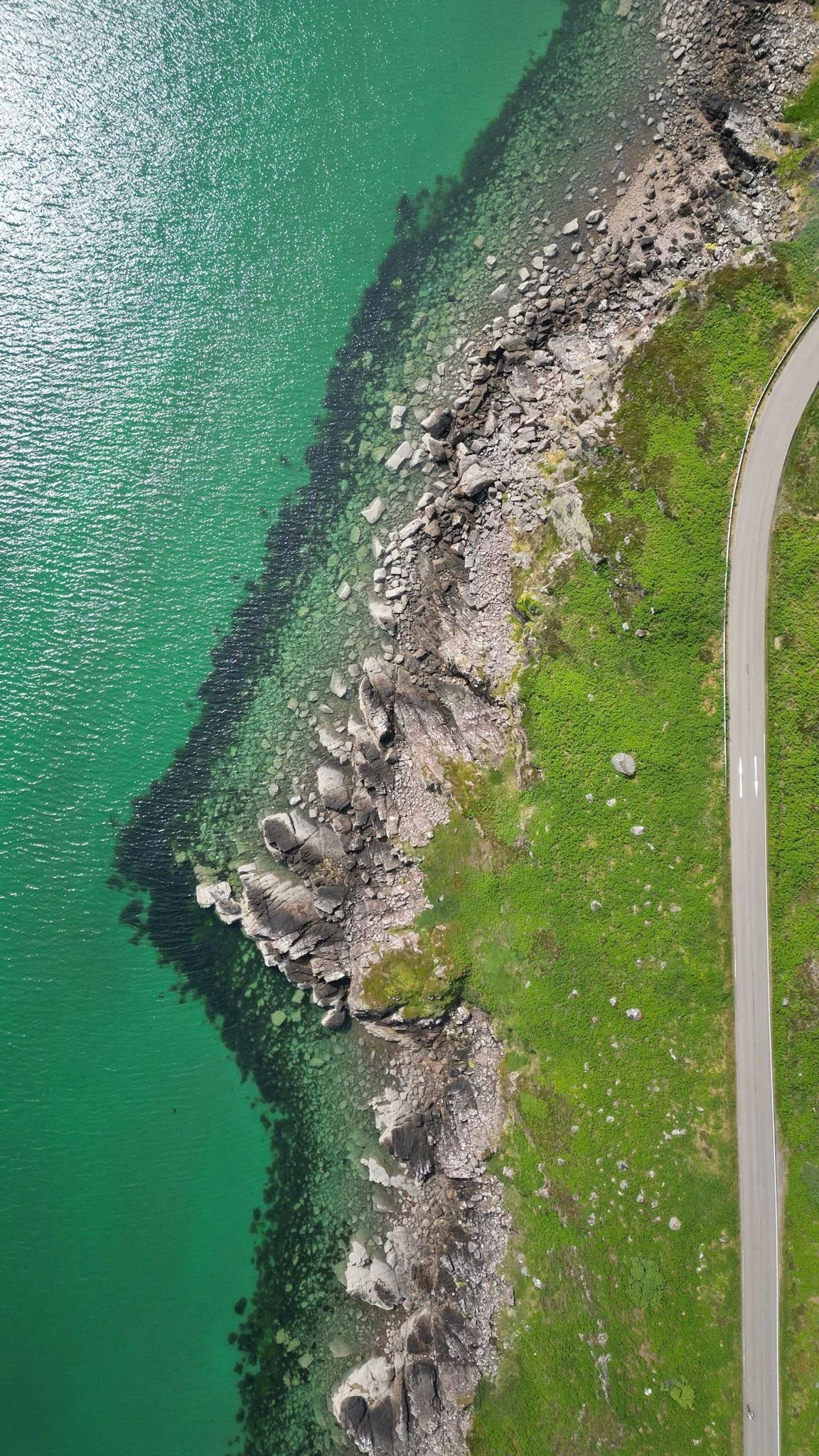 Aerial view of a rocky coastline with clear green water, reflecting calm and openness