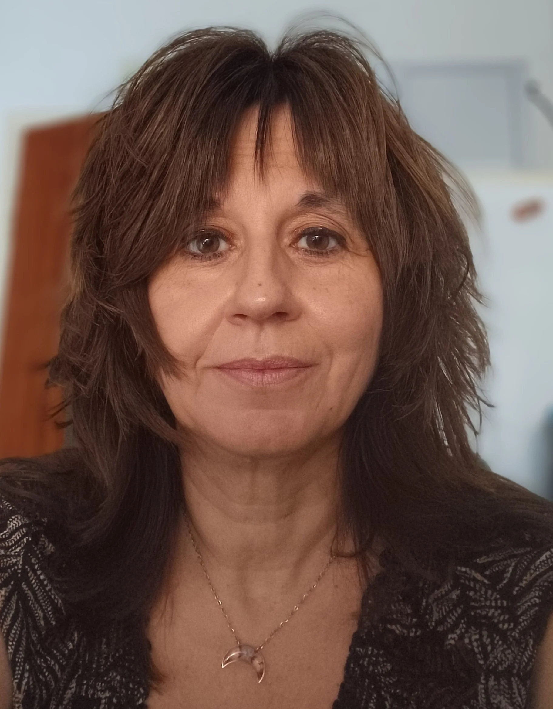 Woman with shoulder length brown hair against a white and brown background