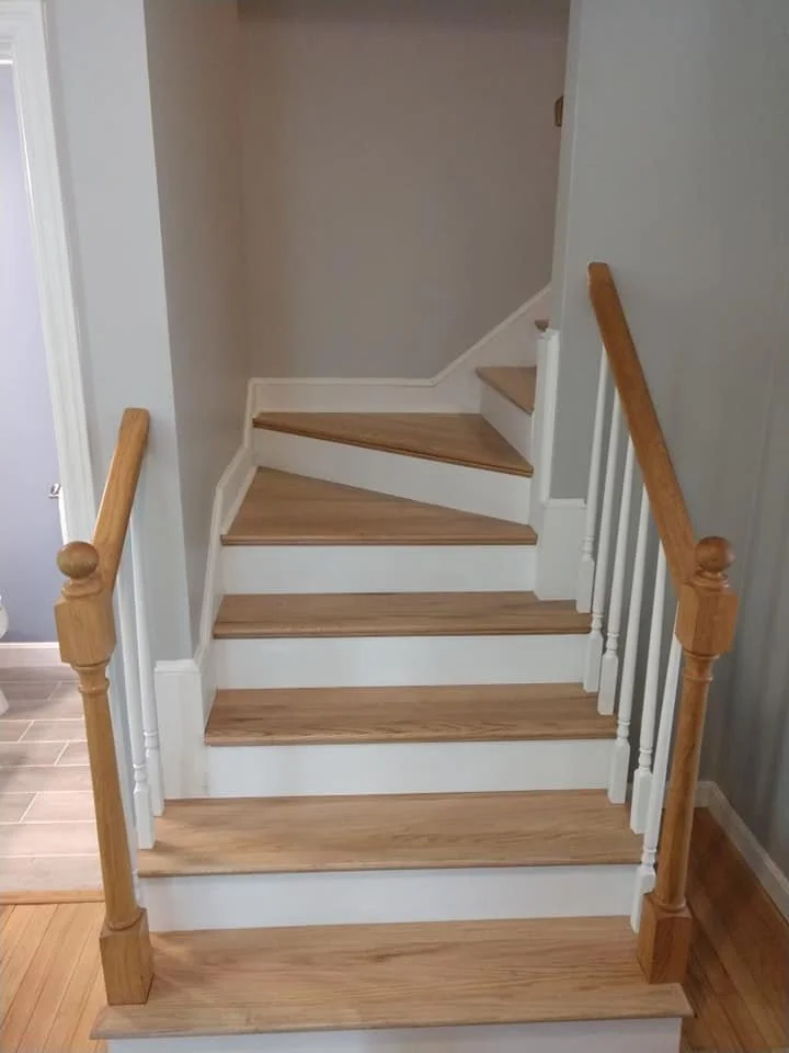 Wooden staircase with white risers and handrails leading to an upper floor in a home interior.
