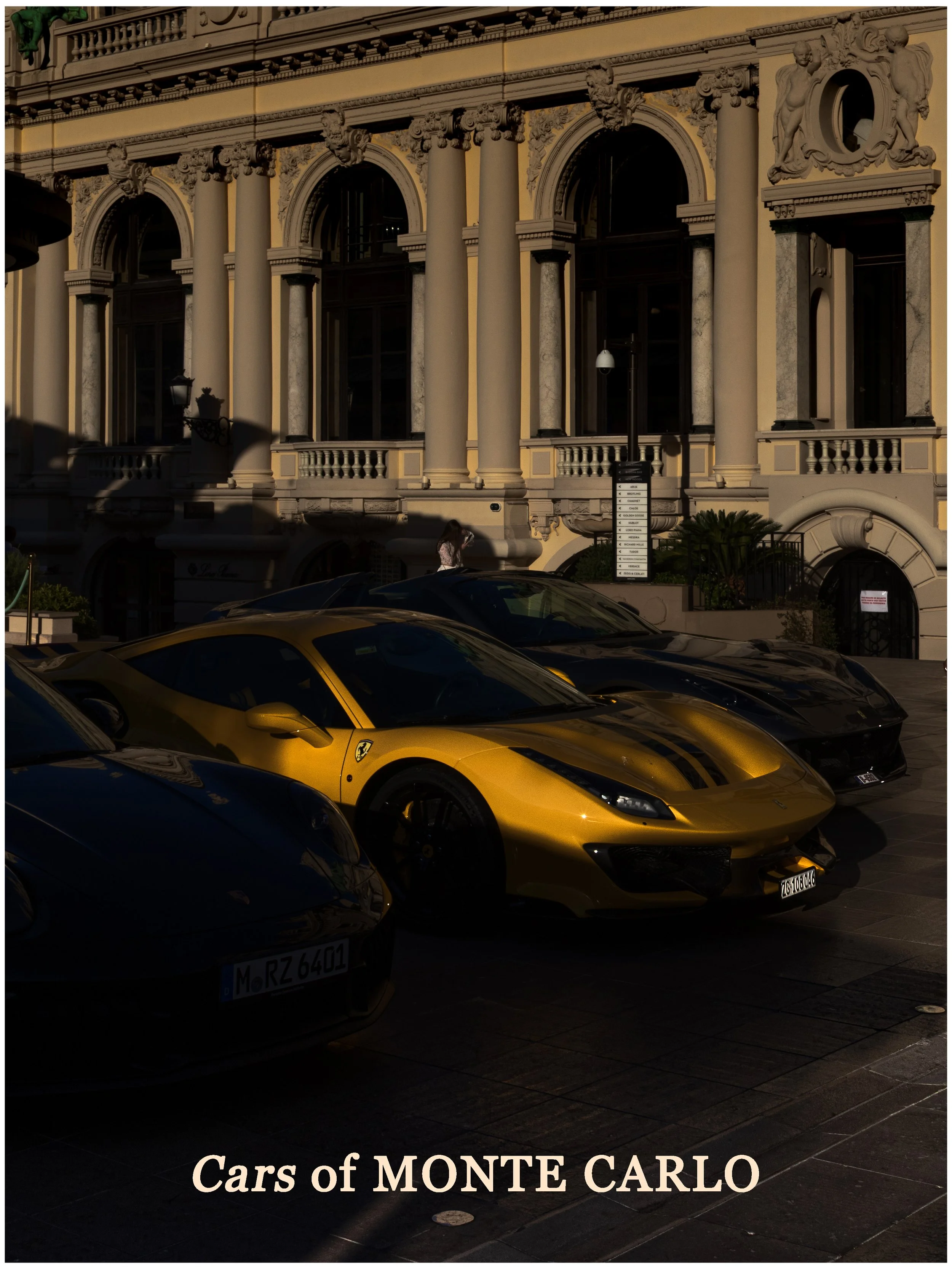 Luxury cars, including a gold Ferrari, parked in front of an ornate historic building in Monte Carlo during daytime.