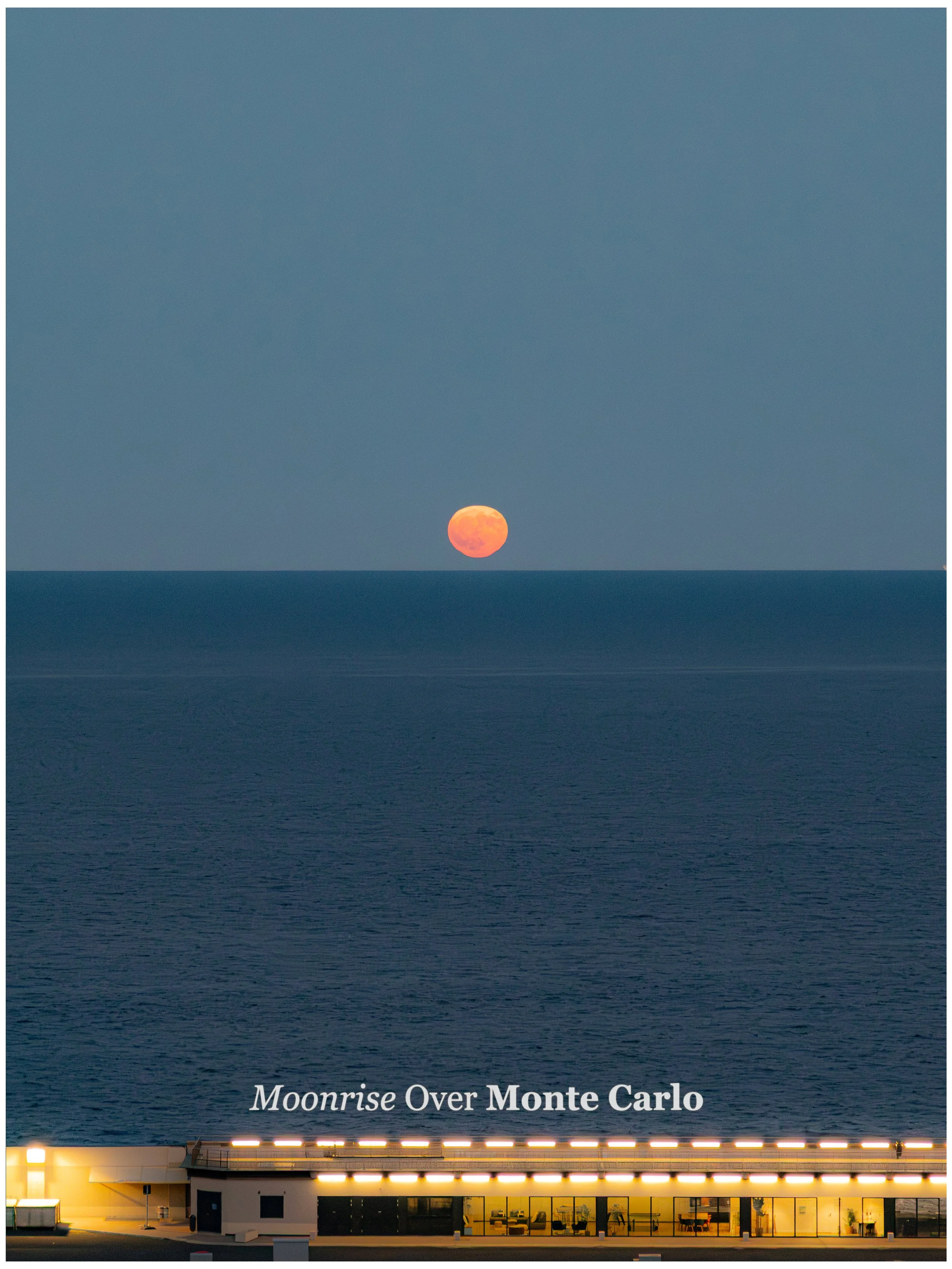 Photograph of a large orange moon rising over the ocean with a building in the foreground, illuminated at night, and the text 'Moonrise Over Monte Carlo' at the bottom.