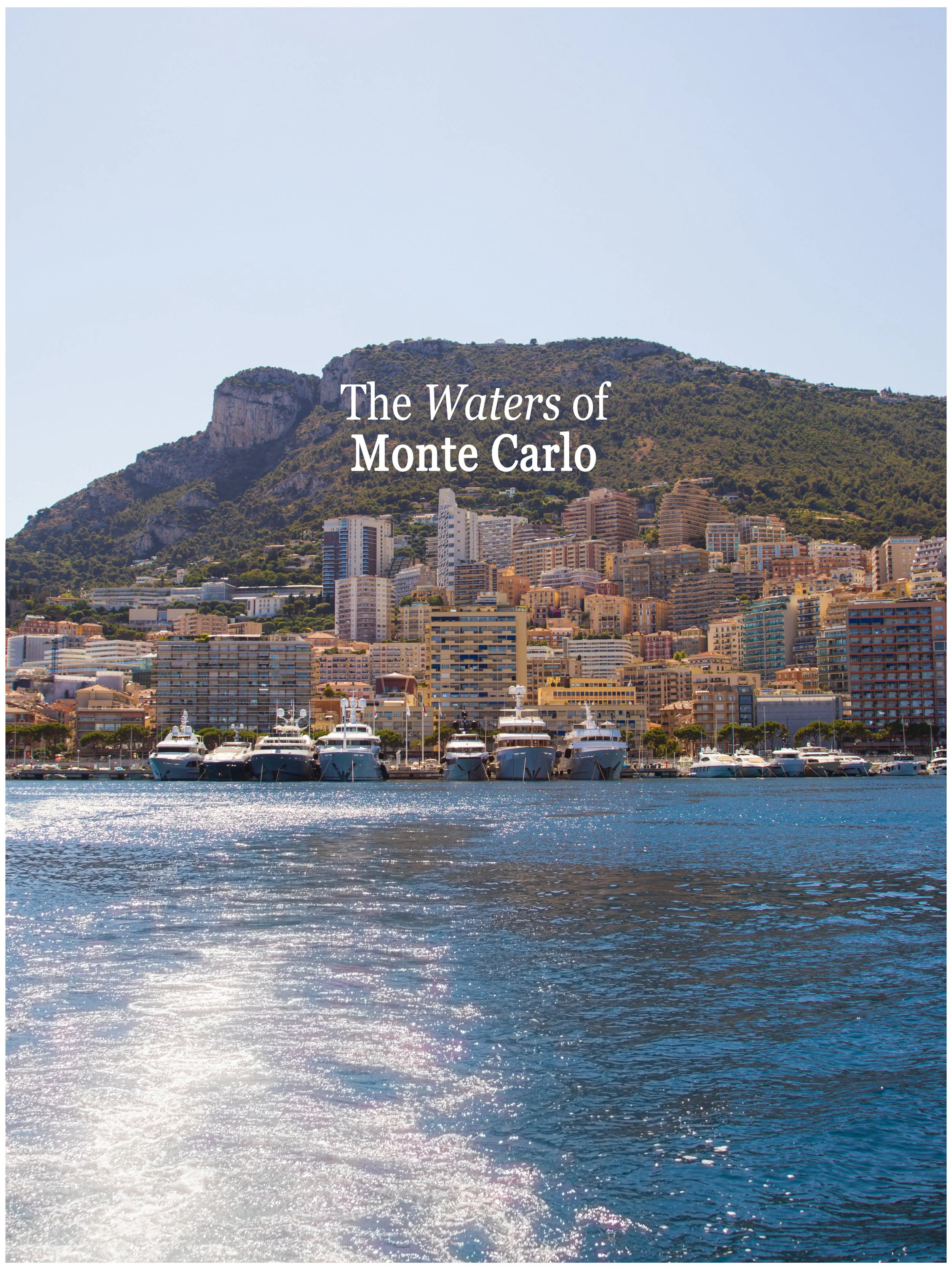 A view of Monte Carlo showing yachts docked in the harbor and high-rise buildings with a mountainous backdrop.