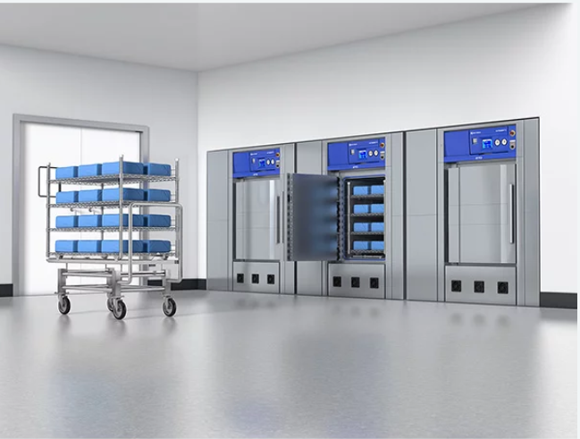 Sterilization room with autoclaves and a rolling cart filled with blue trays.