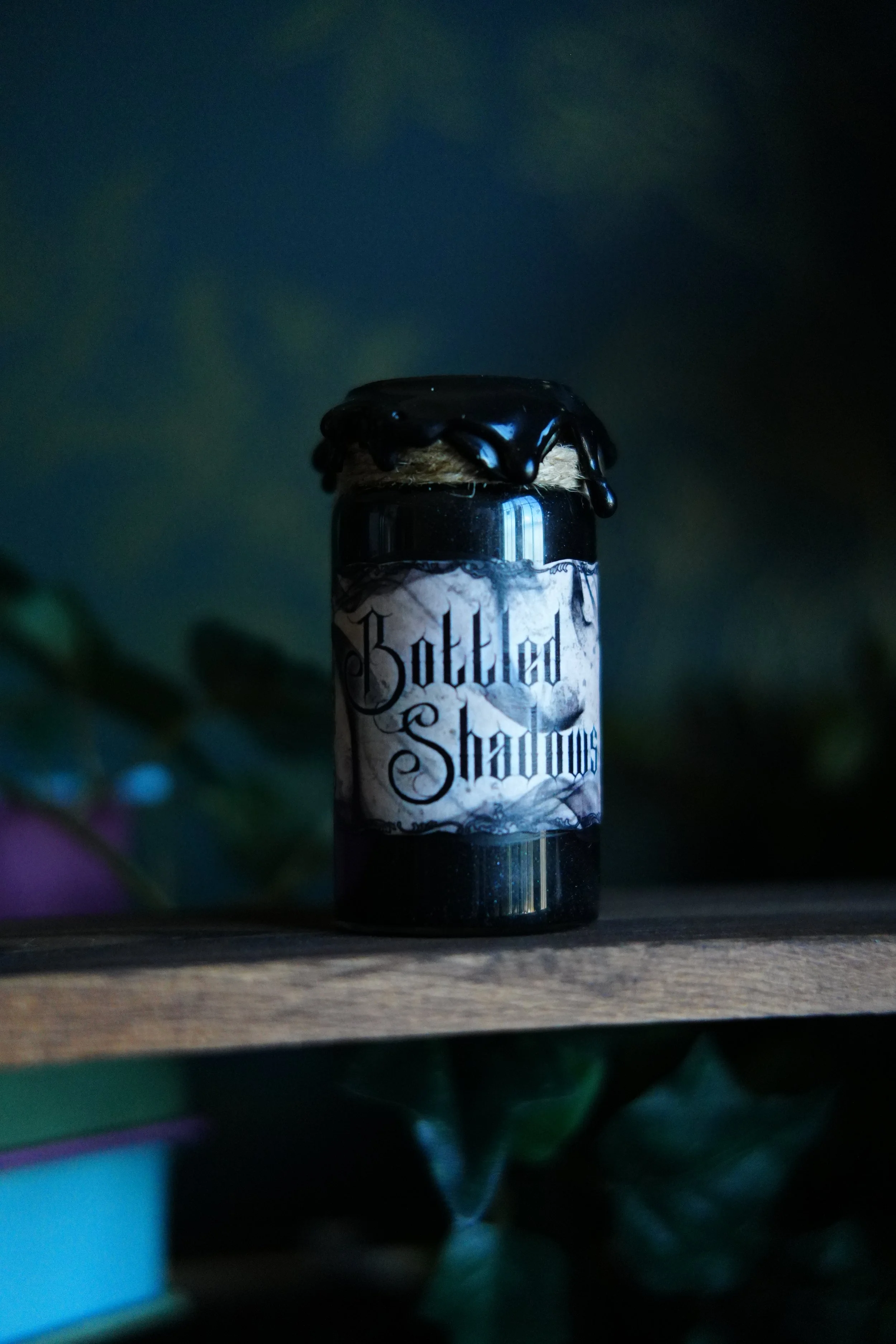 Small, black decorative potion with a label that reads "Bottled Shadows"