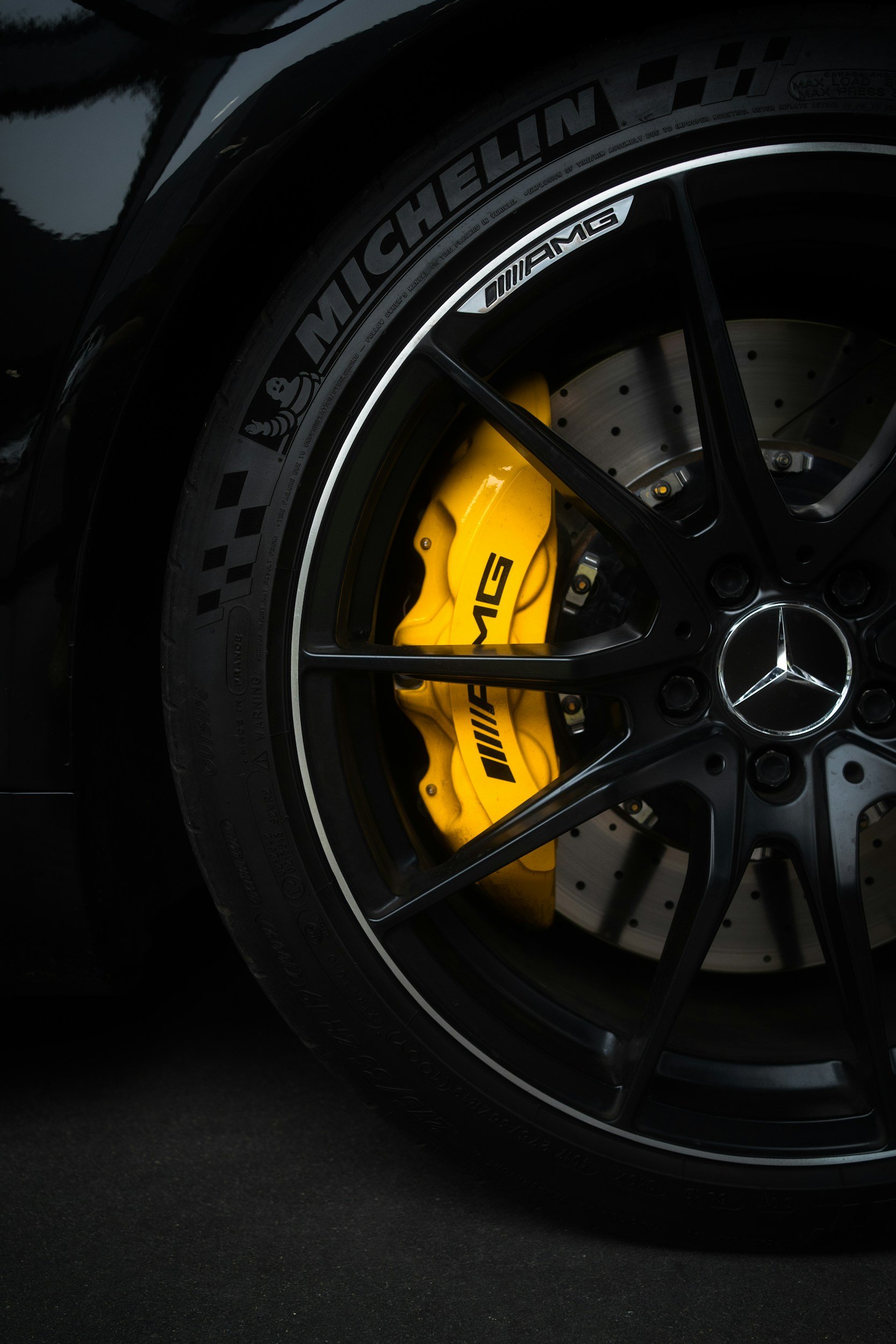 Close-up of a black Mercedes-Benz car wheel with a yellow AMG brake caliper and Michelin tire.