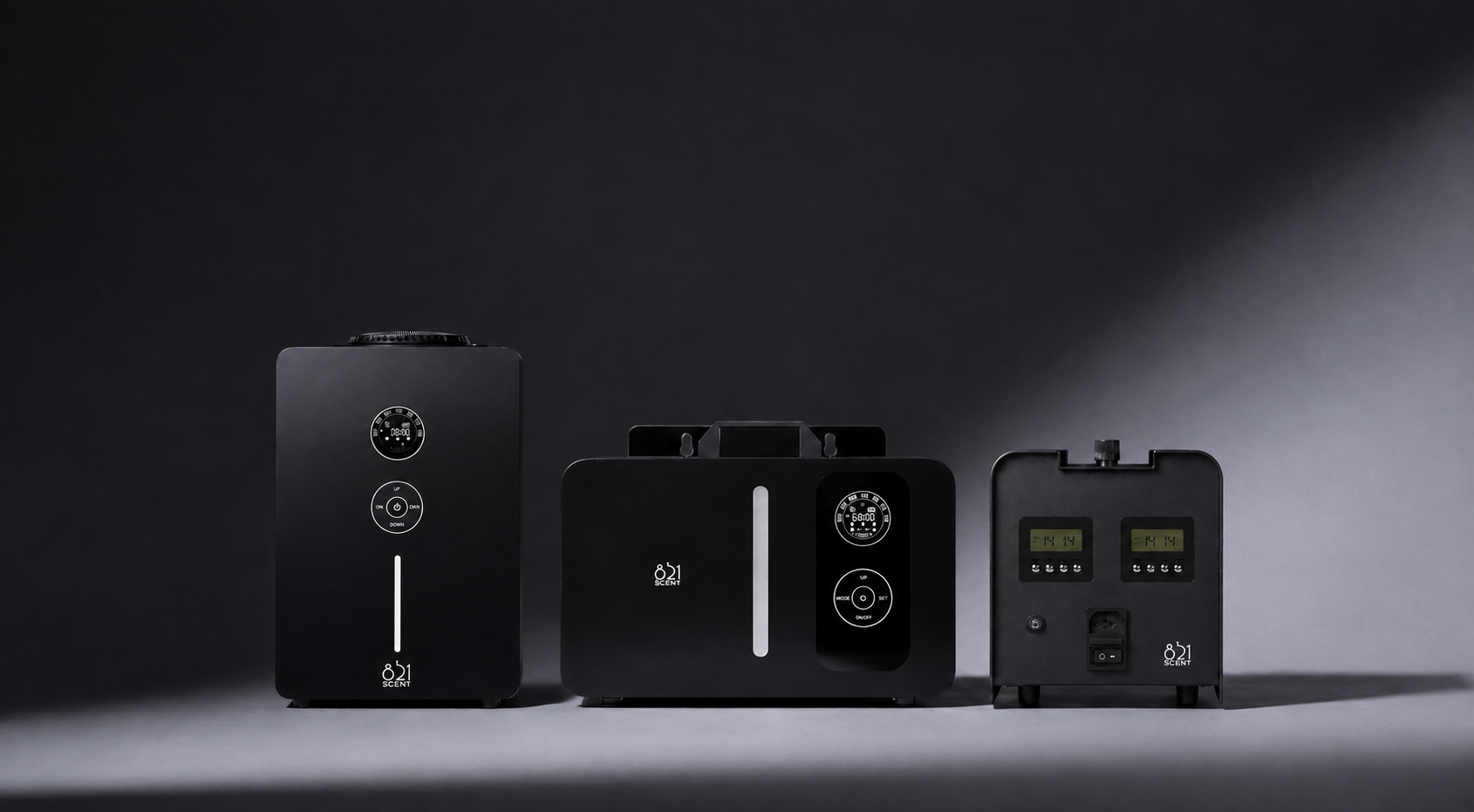 Four black home fragrance diffuser devices with digital displays and control buttons, arranged against a dark gradient background.