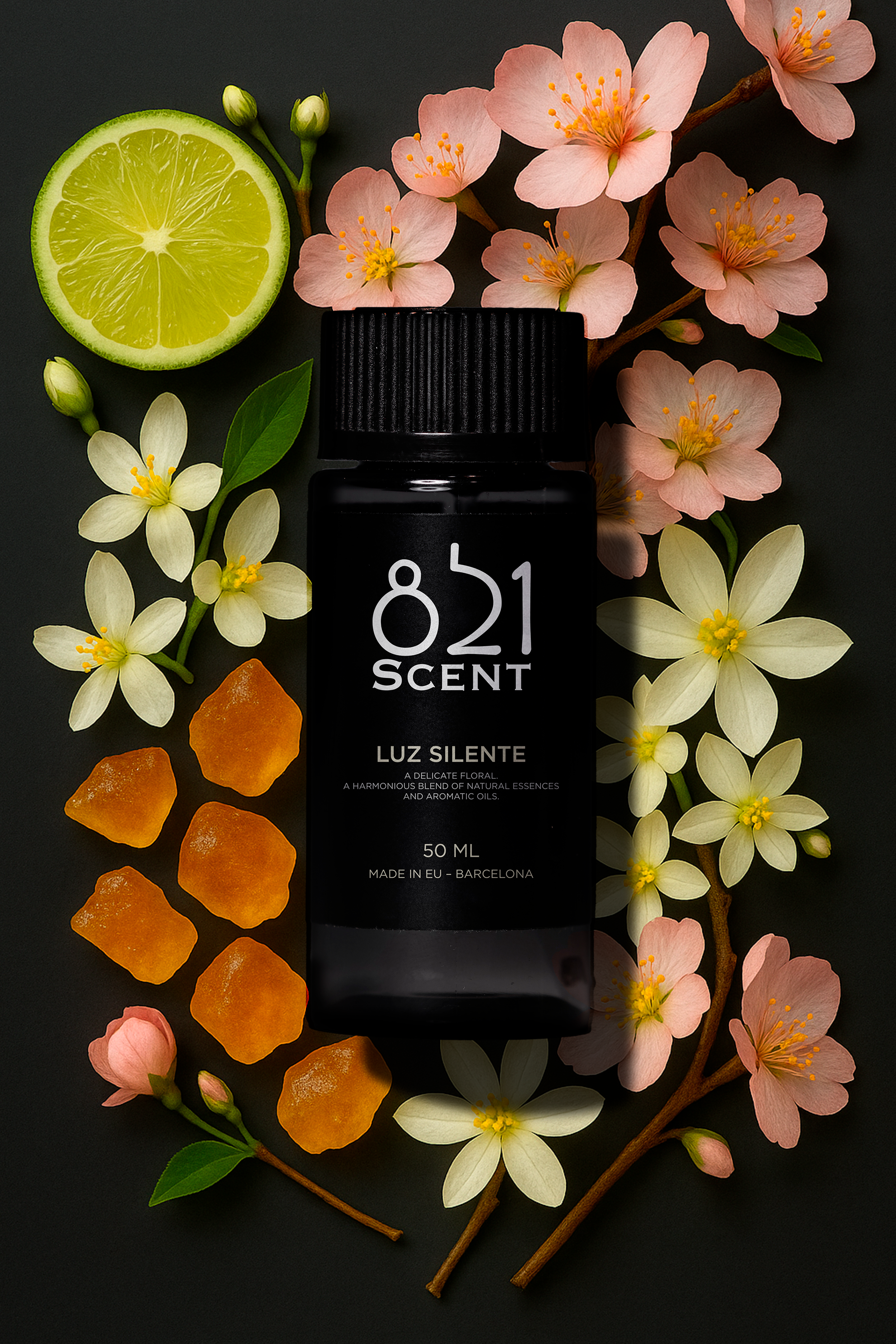 A black bottle labeled '821 Scent Luz Silente' surrounded by a slice of lime, pink cherry blossoms, white jasmine flowers, and orange aromatherapy stones on a dark background.
