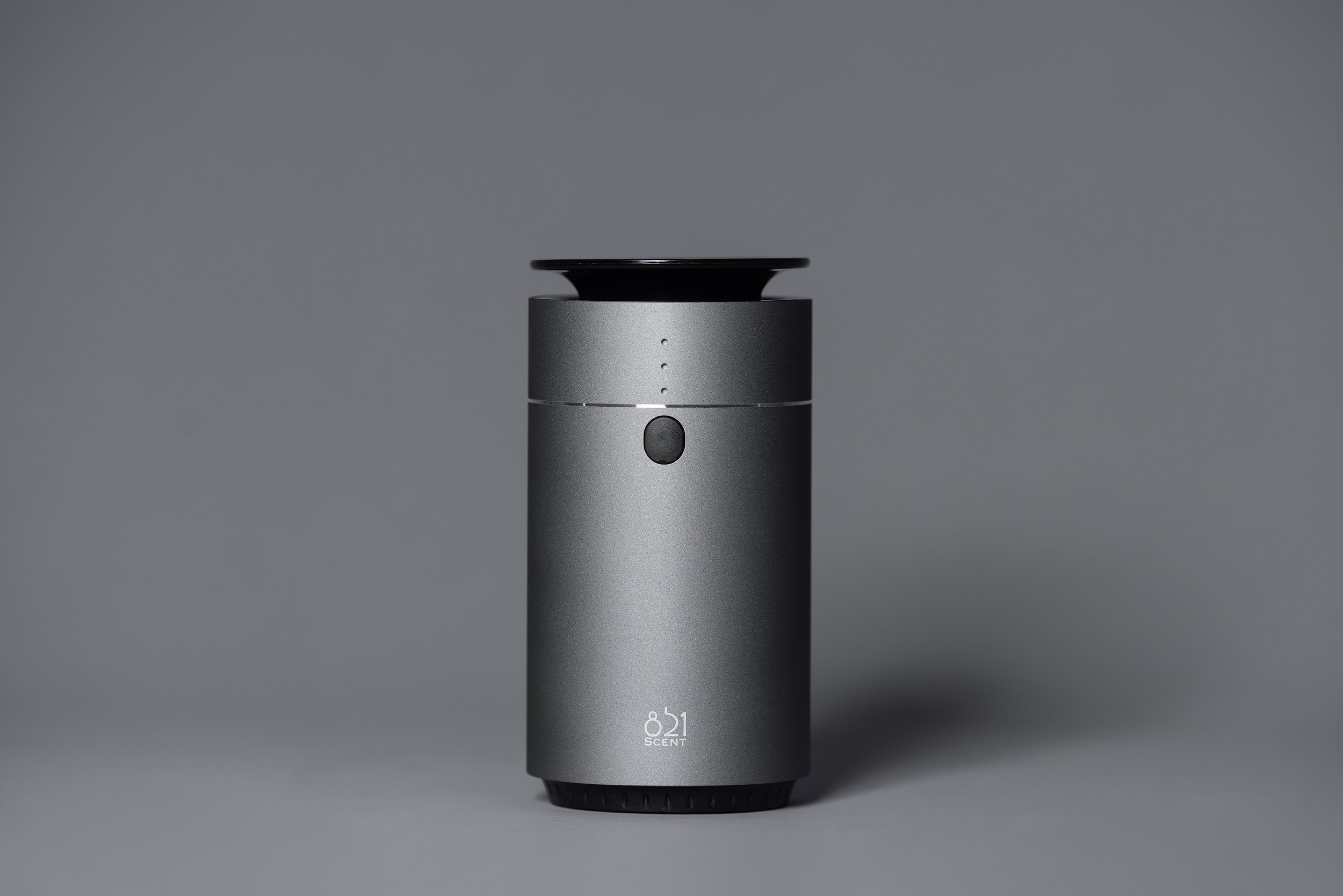 A sleek, modern gray air Diffuser with a black top, a central button, and small indicator lights, labeled '811 SCENT' at the bottom, against a plain gray background.