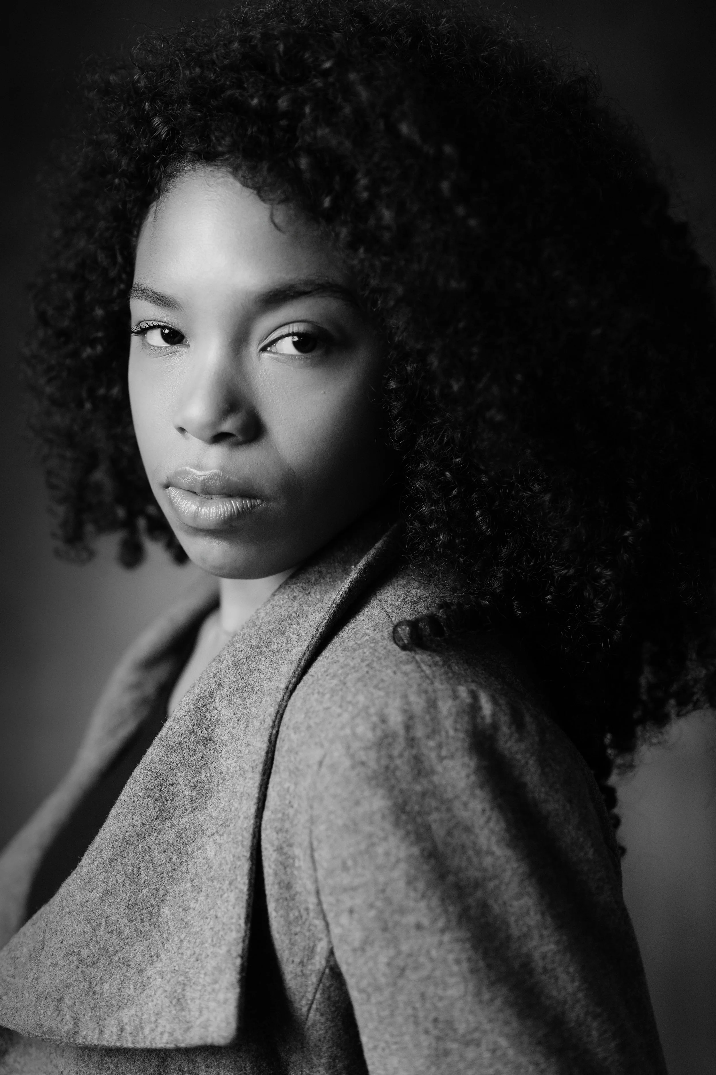 Ritratto in bianco e nero di una donna con capelli ricci e sguardo diretto.