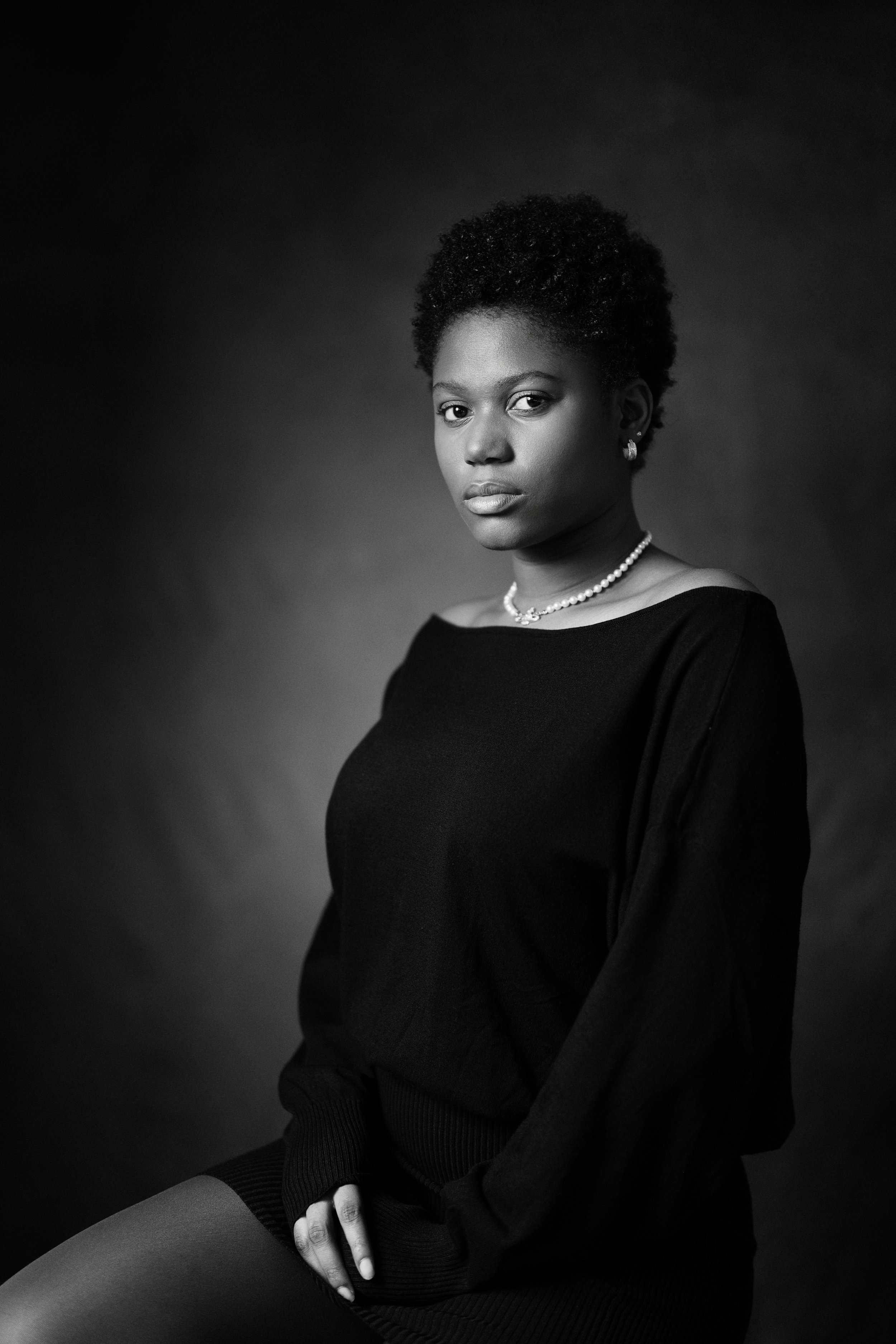 Ritratto in bianco e nero di una donna afroamericana con abbigliamento elegante, collana di perle e orecchini, che guarda verso l'obiettivo.