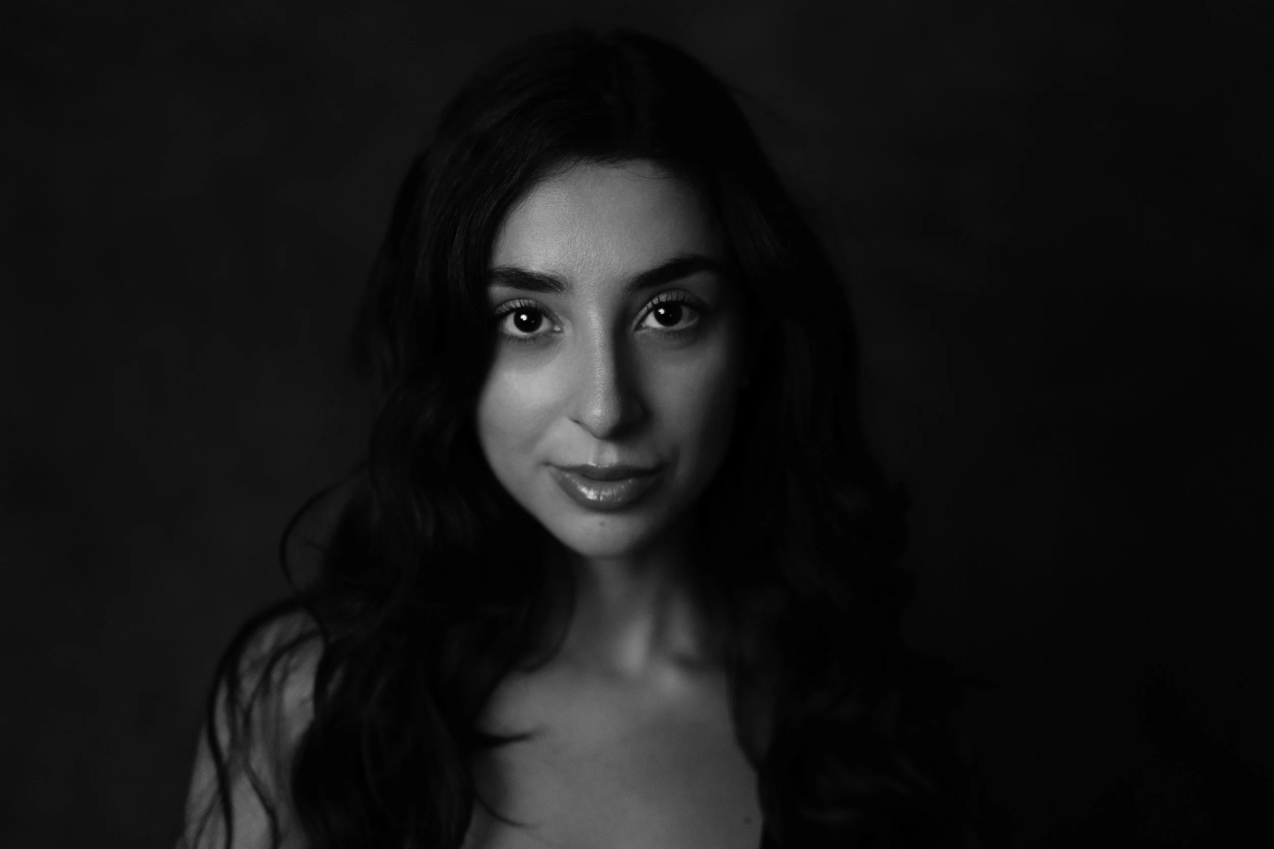 Ritratto in bianco e nero di una donna con capelli lunghi e mossi, che guarda direttamente davanti a sé.