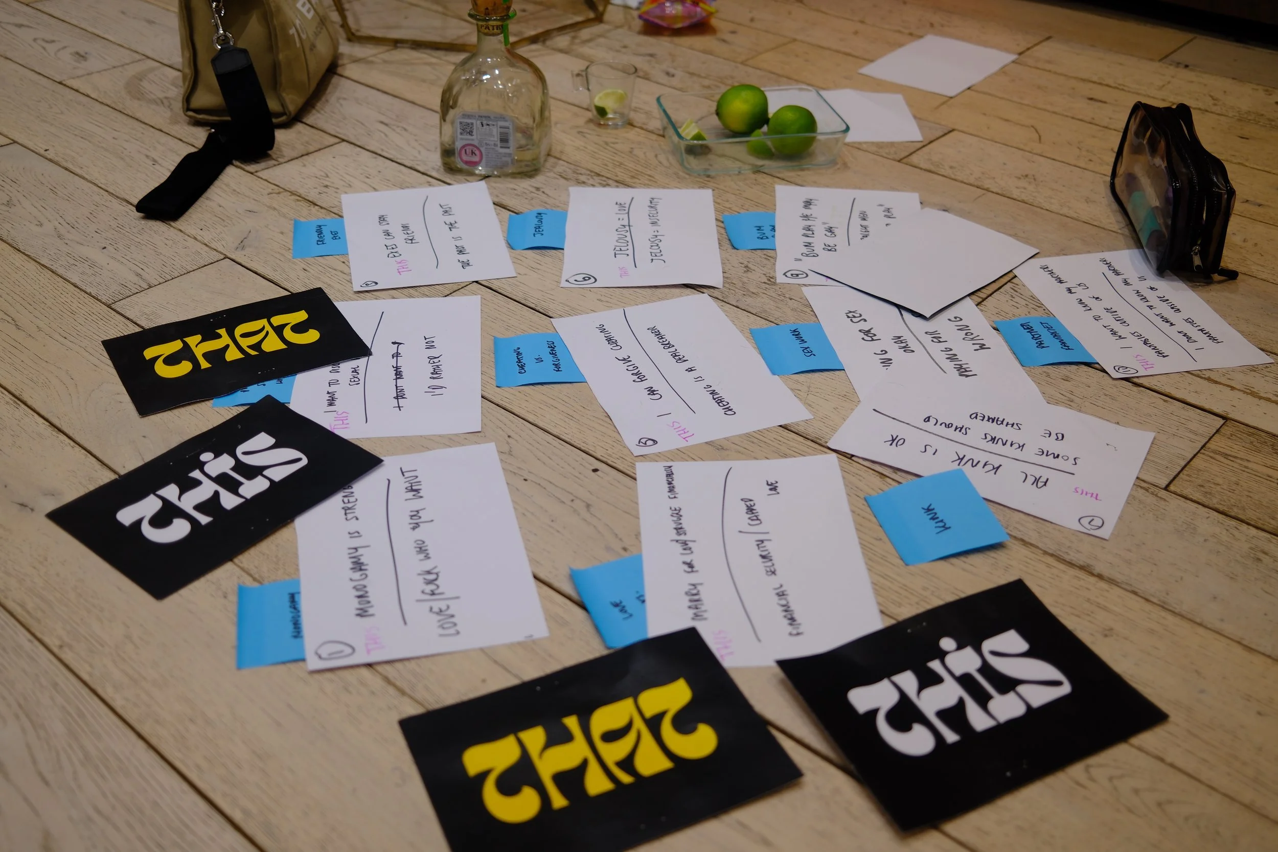 Notes, stickers, and containers scattered on a wooden floor, with two black and yellow 'THRIVE' stickers and a black and white sticker visible among the papers.
