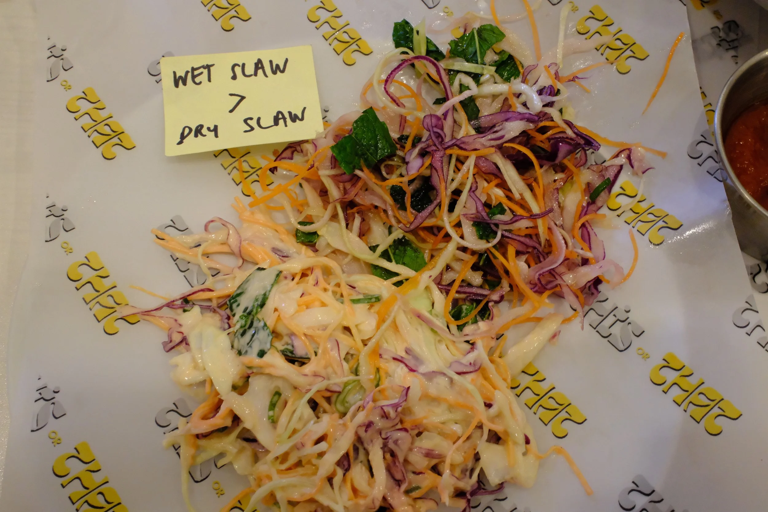 Assorted coleslaw salads on paper with a note indicating wet slaw on top and dry slaw below.