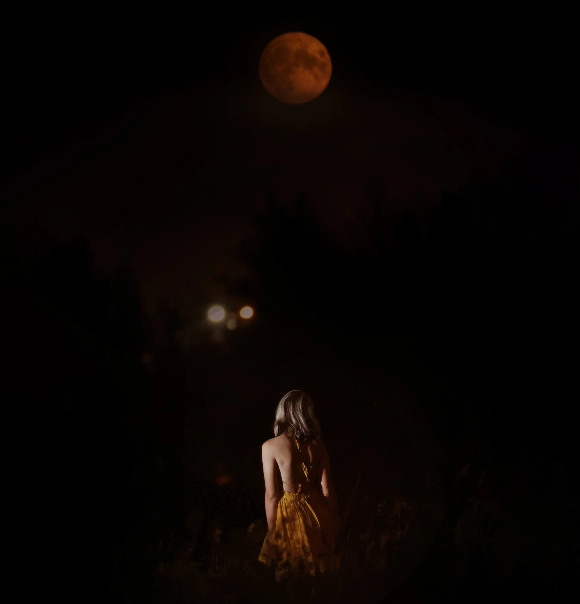 a woman sitting under the full moon at night