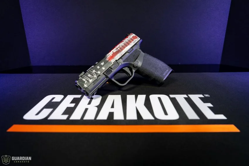 A black handgun with a red, white, and blue American flag design on the slide, placed on a Cerakote surface.