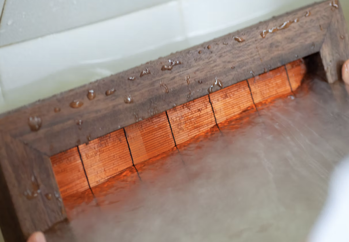 Close-up of a traditional wooden water brush with inkstone, used for calligraphy or painting, covered in water droplets.
