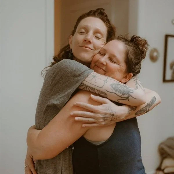 Two women hugging each other warmly with smiles on their faces.