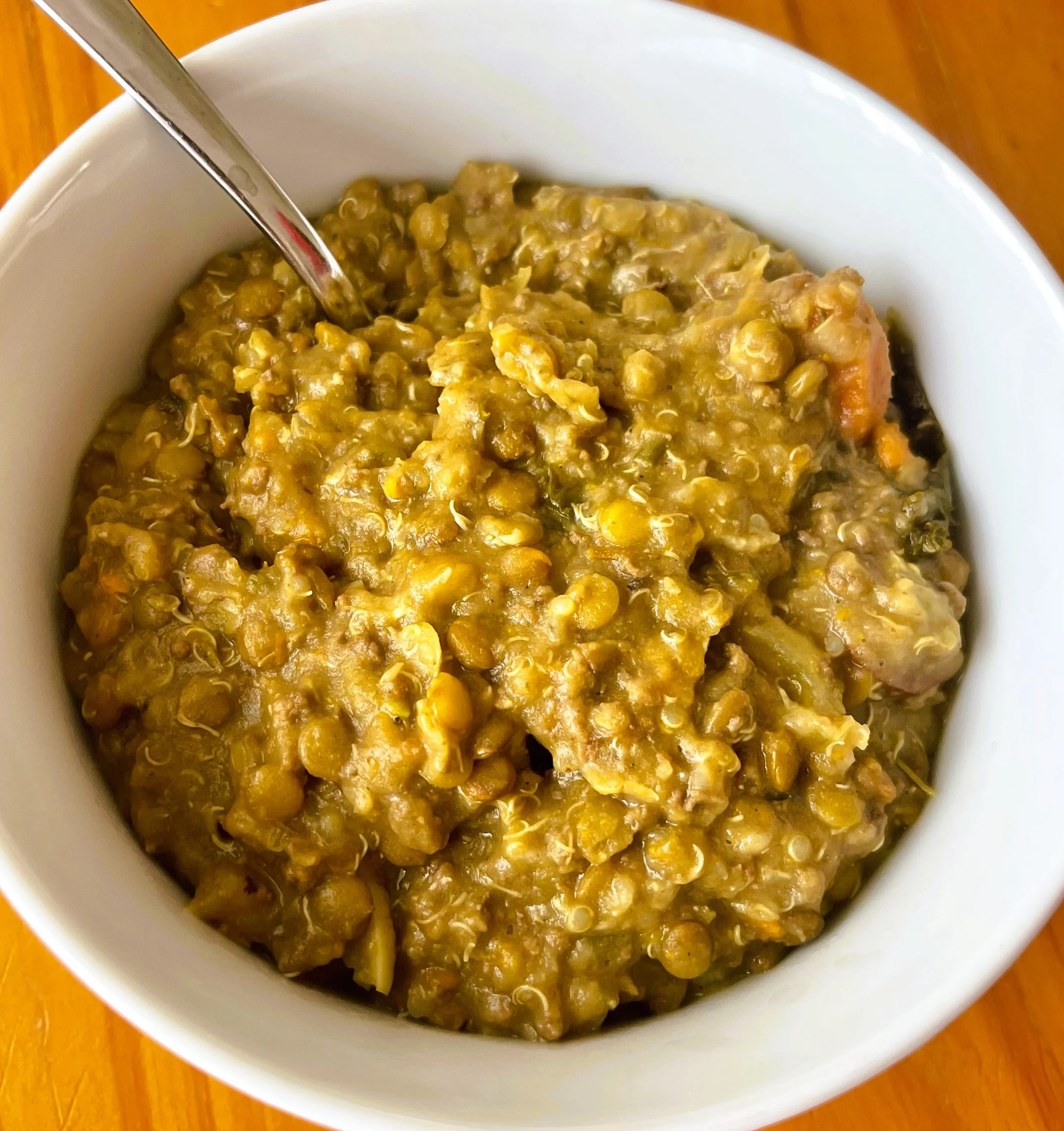 Bowl of cooked Lentil beef stew with a spoon.