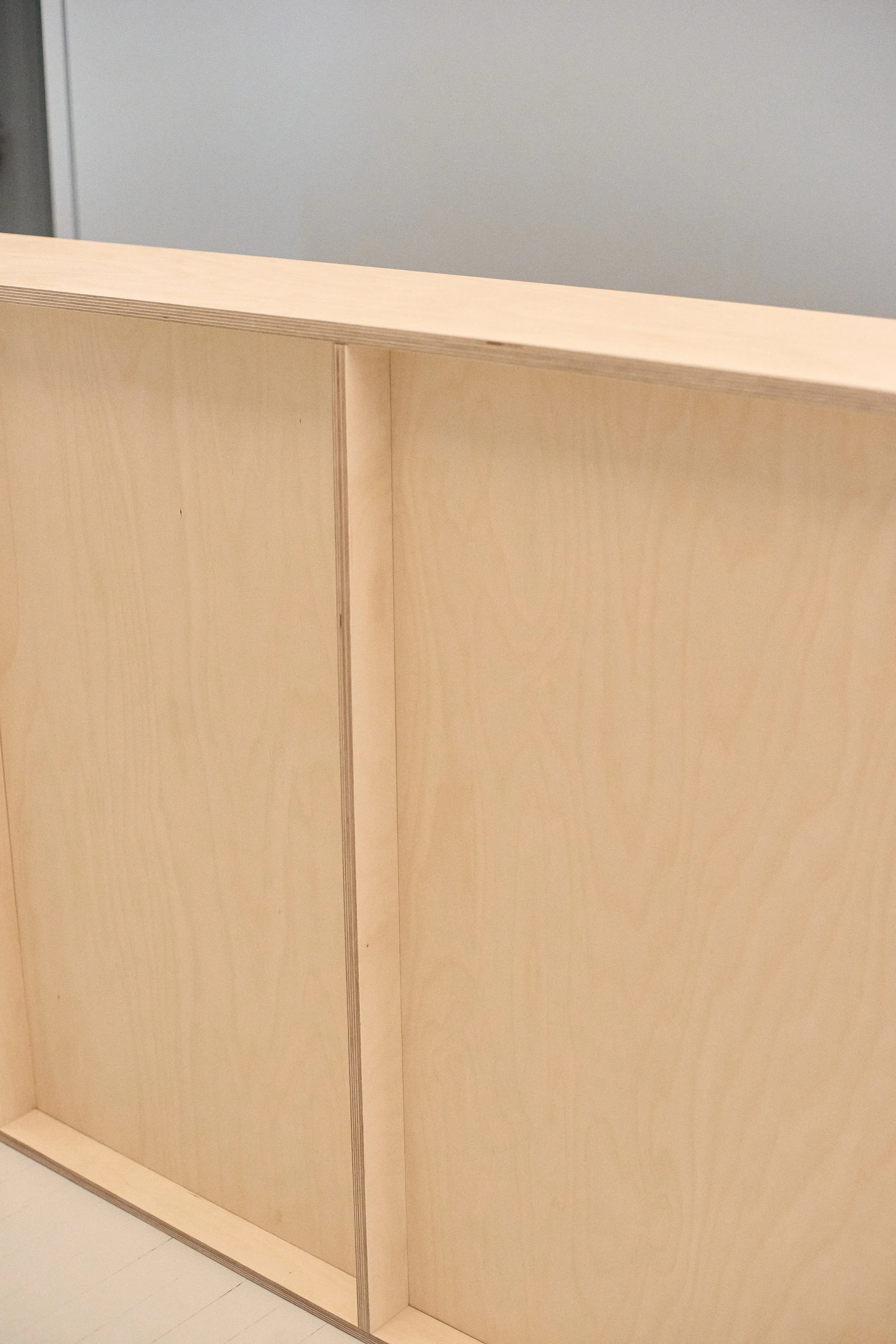 Plywood reception desk detail showing clean lines and warm wood grain.
