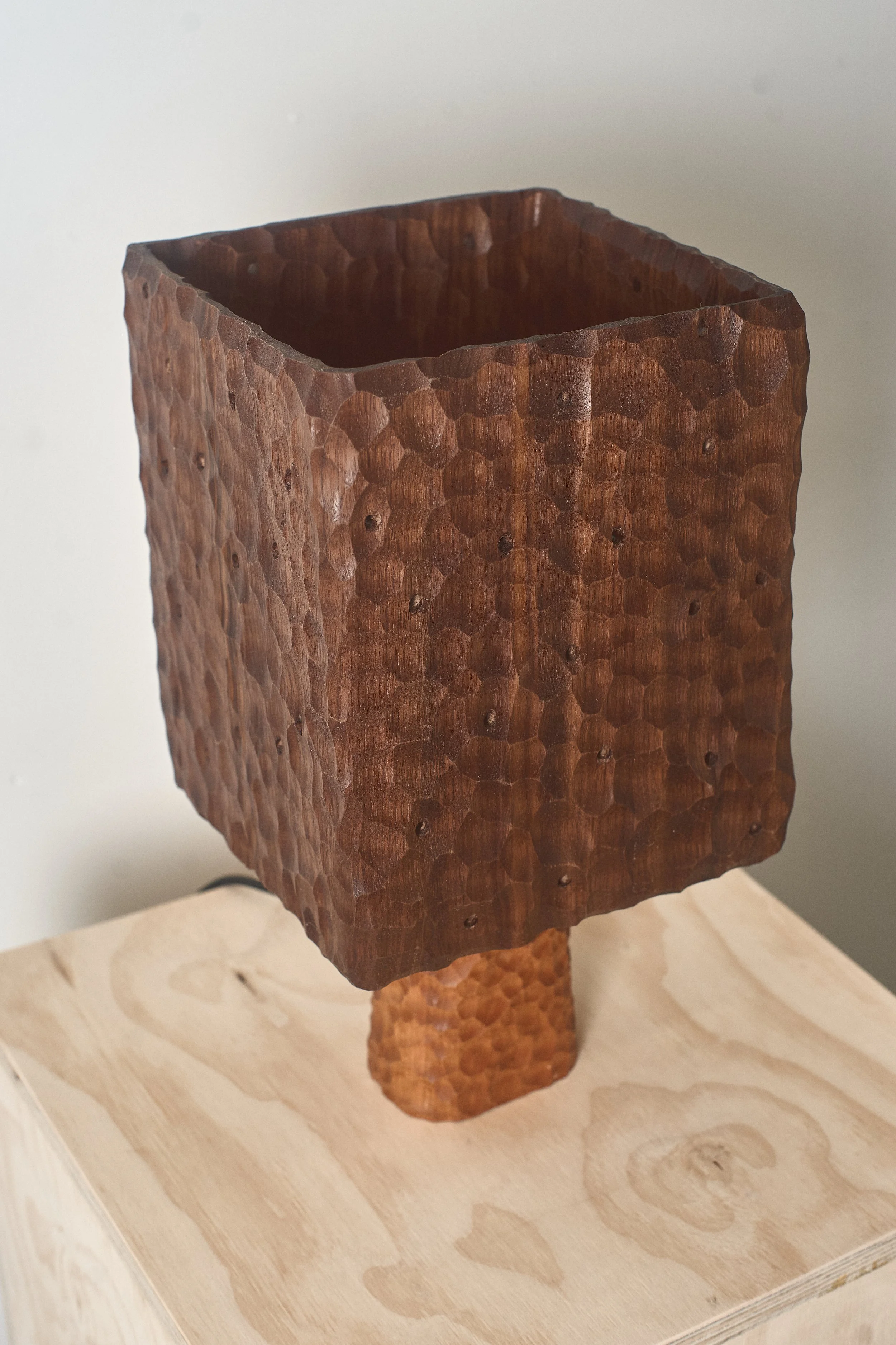 Hand-carved cherry lamp base showing the sculpted surface and natural wood grain.