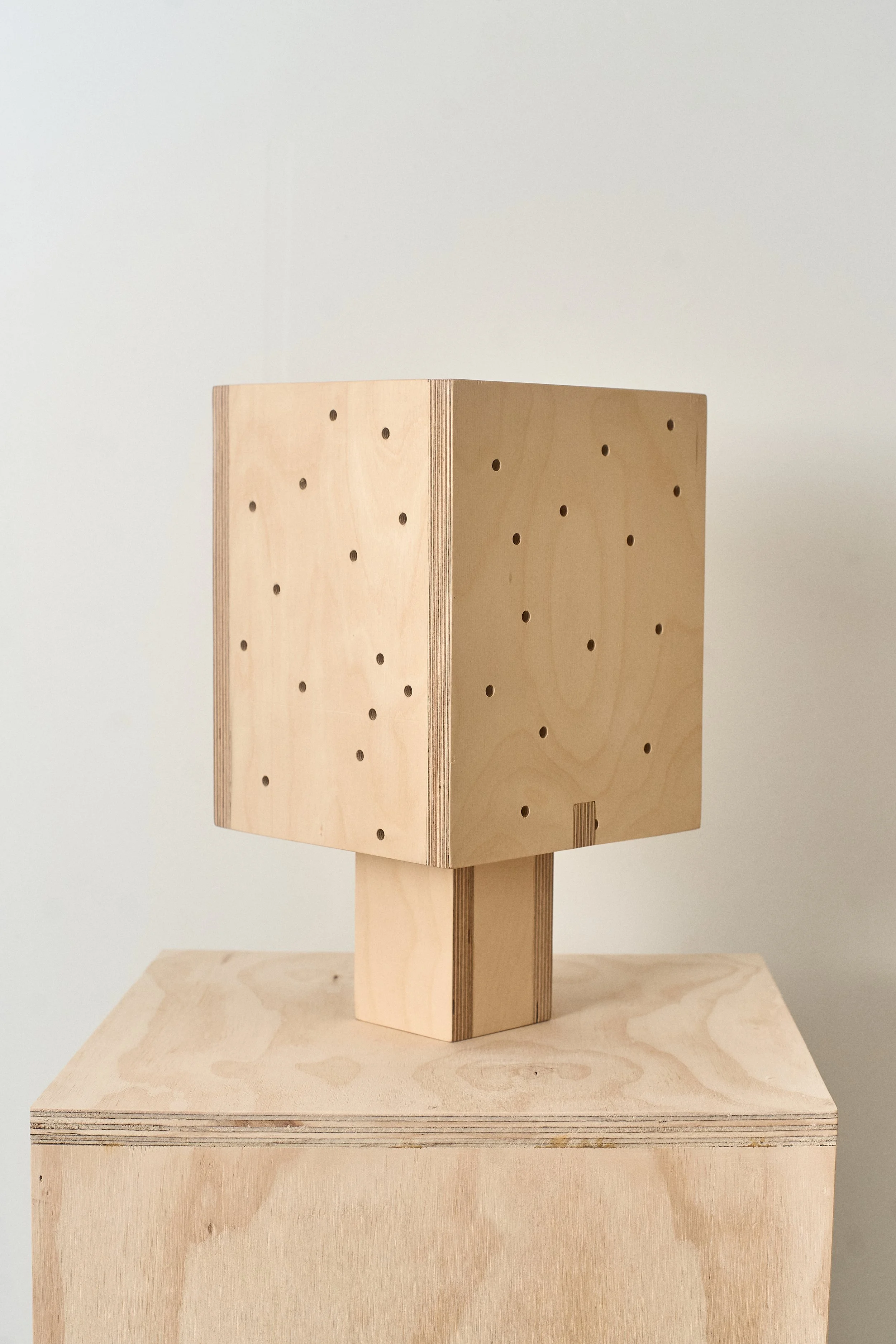 Plywood table lamp showing its clean form and warm illuminated surface.